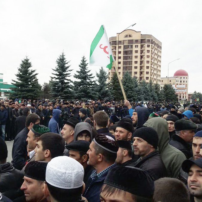 الصورة تظهر تجمعًا حاشدًا من الناس في منطقة حضرية. يبدو أن المحتشدين يرتدون ملابس متنوعة، وهناك بعضهم يحملون لافتات أو أعلام. في الخلفية، توجد مبانٍ شاهقة وأشجار، مما يشير إلى أن هذا التجمع يمكن أن يكون حدثًا اجتماعيًا أو سياسيًا. تبدو السماء ملبدة بالغيوم، مما يعكس أجواء غير مشمسة.