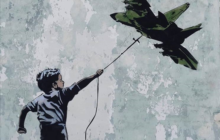 L'image représente un garçon courant joyeusement, tenant une ficelle à laquelle est suspendu un avion de chasse. Le mur en arrière-plan est rugueux et décoloré, ce qui met en valeur le contraste entre la figure du garçon et l'avion. Cette œuvre pourrait symboliser des thèmes comme l'innocence de l'enfance face à la guerre ou la rêverie de l'évasion.