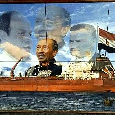 L'image présente une fresque murale qui montre un grand cargo au premier plan, naviguant sur l'eau. En arrière-plan, plusieurs portraits en superposition de différentes figures politiques égyptiennes, évoquant probablement des présidents ou dirigeants historiques. L'ensemble crée une composition qui semble célébrer l'histoire maritime et politique de l'Égypte, en particulier autour du canal de Suez. Des éléments graphiques comme le logo du canal et une carte en haut à droite ajoutent au contexte maritime.