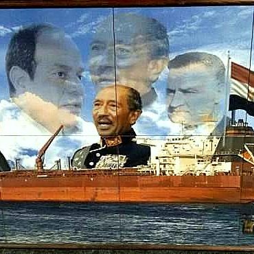 الصورة تُظهر لوحة فنية تتضمن عدة شخصيات تاريخية معروفة، وهي مرتبطة بقناة السويس. في الوسط يظهر سفينة ضخمة تبحر، محاطة بصور لعدد من الشخصيات التاريخية، ربما تعكس مراحل مختلفة من تاريخ مصر والقرارات التي اتُخذت بشأن القناة. الخلفية تحتوي على ملامح من البحر، مما يضيف إلى السياق البحري. اللوحة تعبر عن الفخر الوطني والتاريخ البحري لمصر.