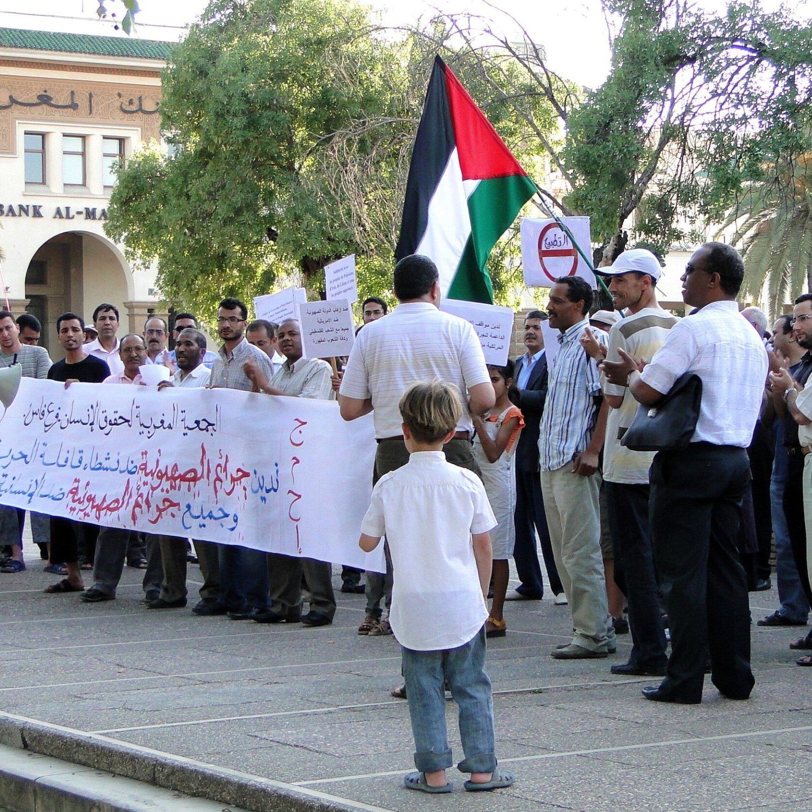 Un gruppo di persone in protesta con bandiera palestinese e striscioni.