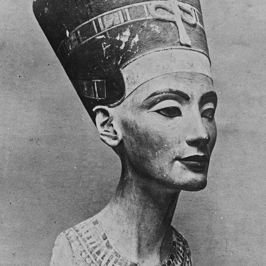 L'immagine rappresenta un busto di pietra di una figura femminile, noto per essere la regina Nefertiti, famosa per la sua bellezza e per il suo ruolo nella storia dell'antico Egitto. Il busto è caratterizzato da un copricapo distintivo e da dettagli elaborati sulla collana e sul viso. La scultura ha un aspetto realistico e raffinato, evidenziando l'arte egizia antica. Il colore della pietra è chiaro con alcune dorature, e l'espressione del volto è serena e dignitosa.