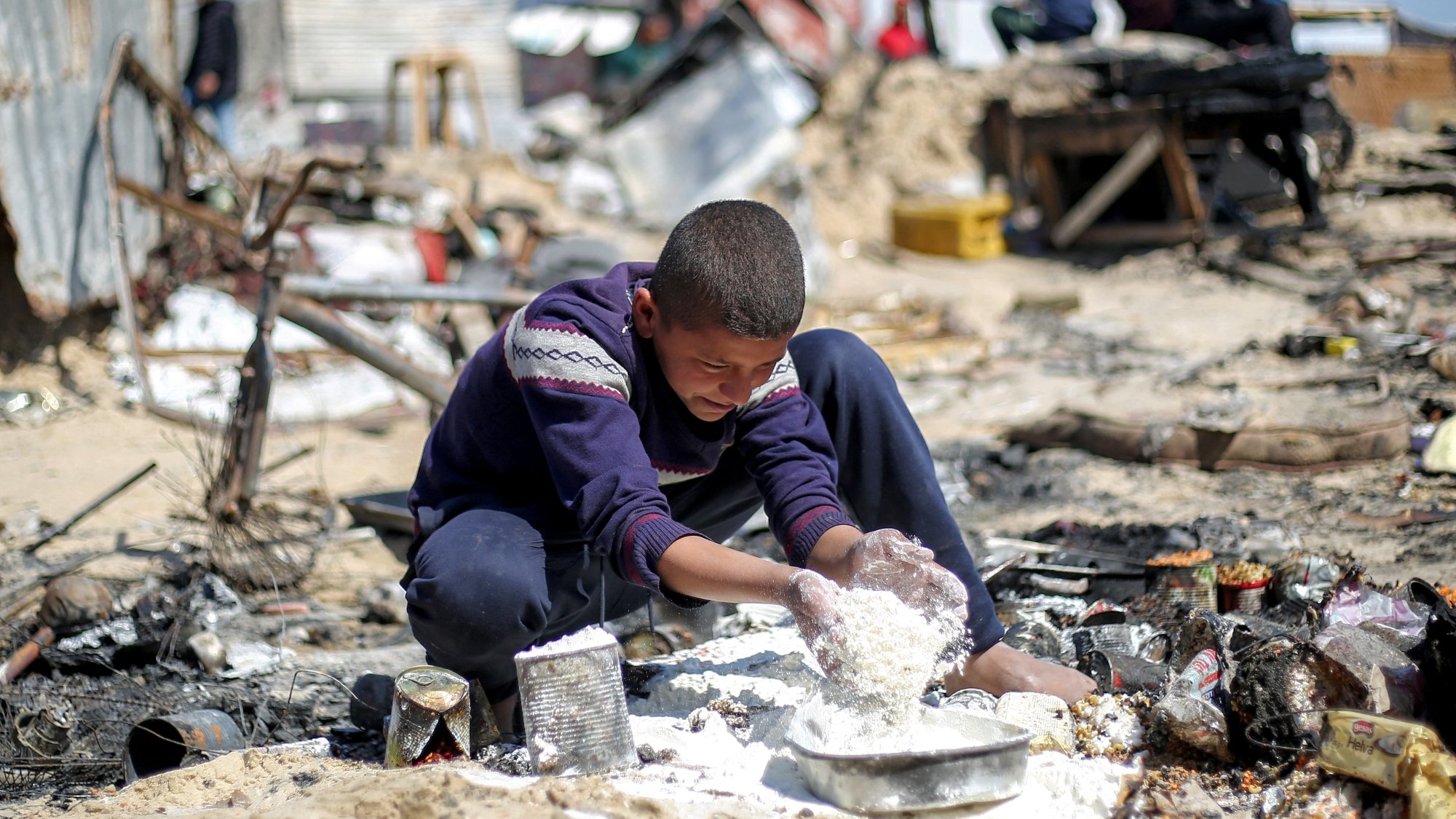 Un garçon joue dans un environnement désordonné, entouré de débris et de ruines.
