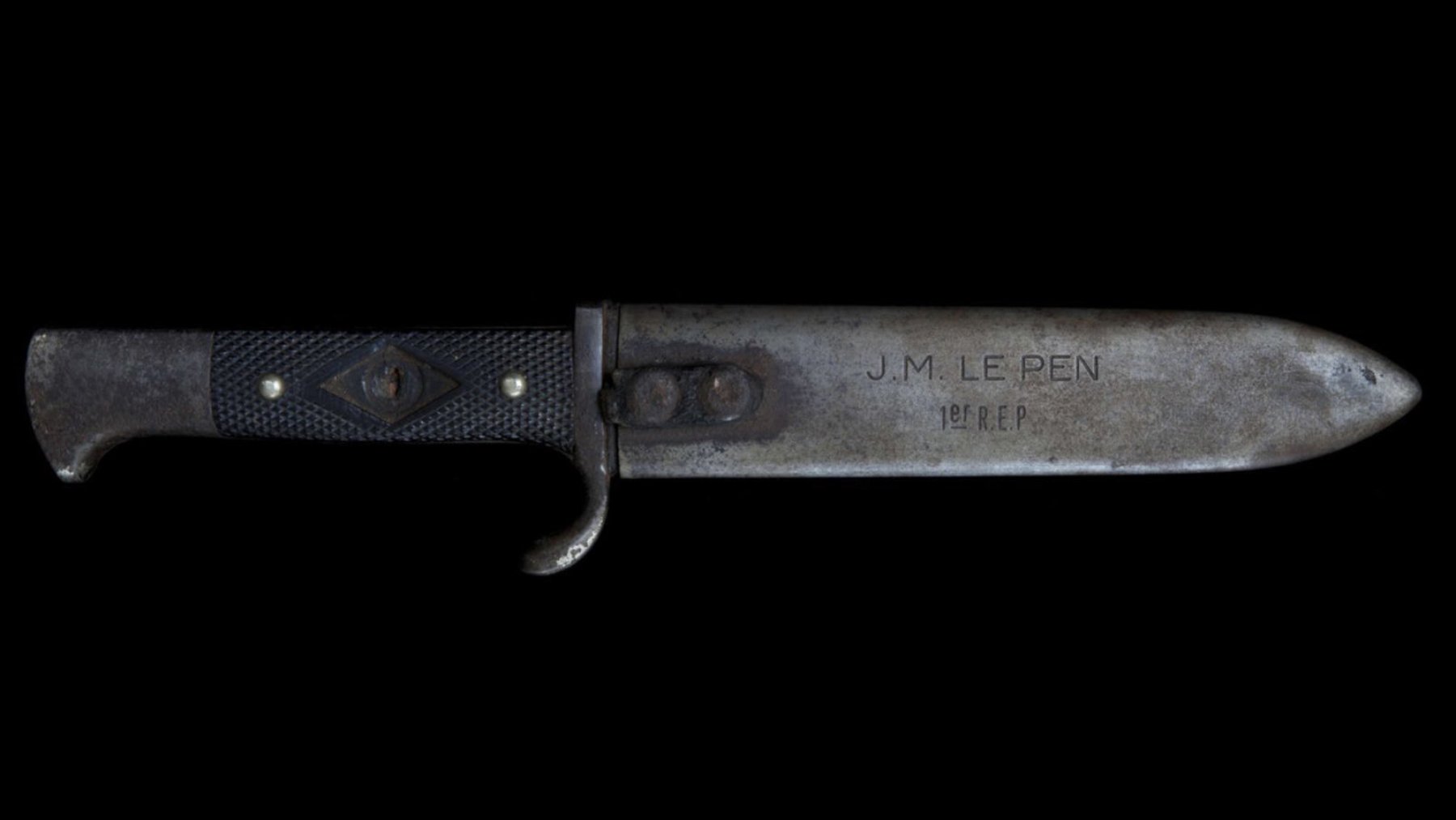 Un couteau avec une lame métallique et un manche noir, gravé d'inscriptions.