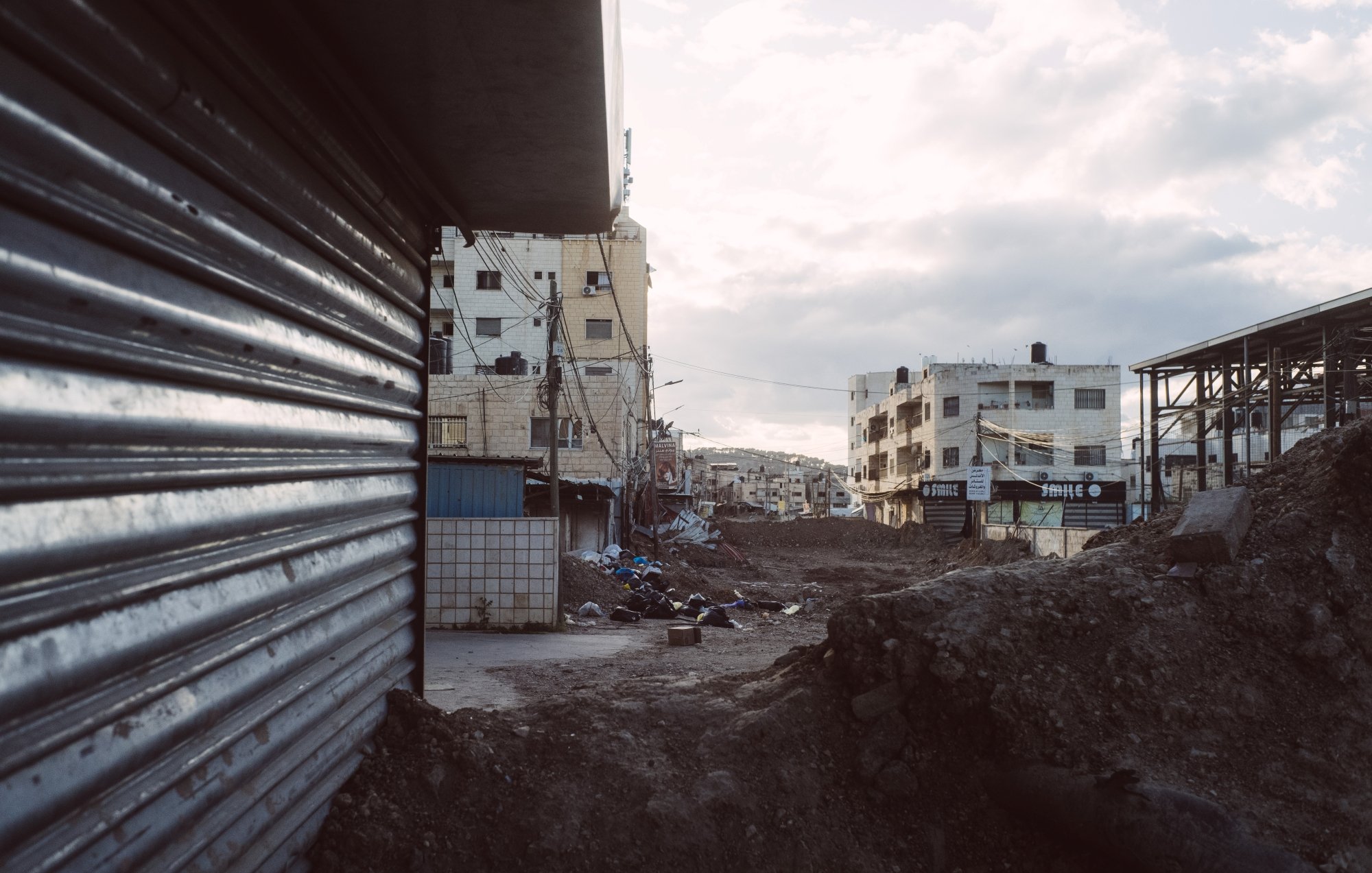 Strade deserte con edifici e terreni in costruzione, atmosfera grigia e cupa.