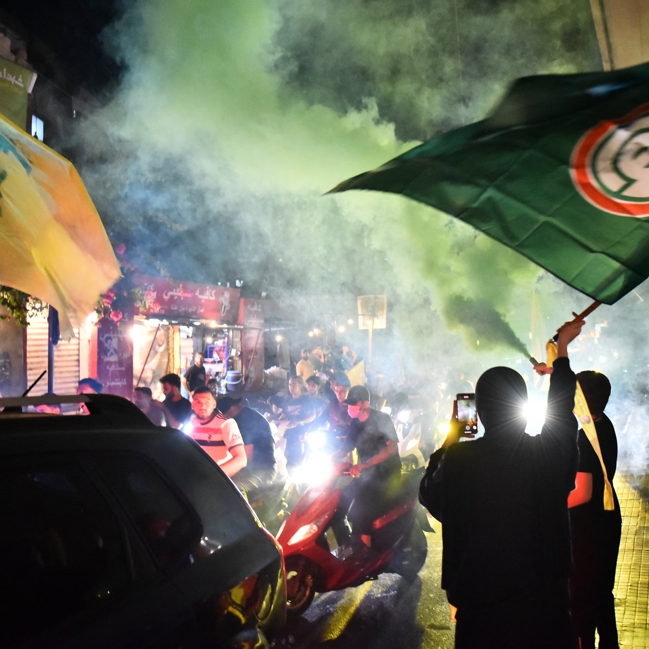 Des manifestants brandissent des drapeaux sous une fumée colorée dans une ambiance festive.