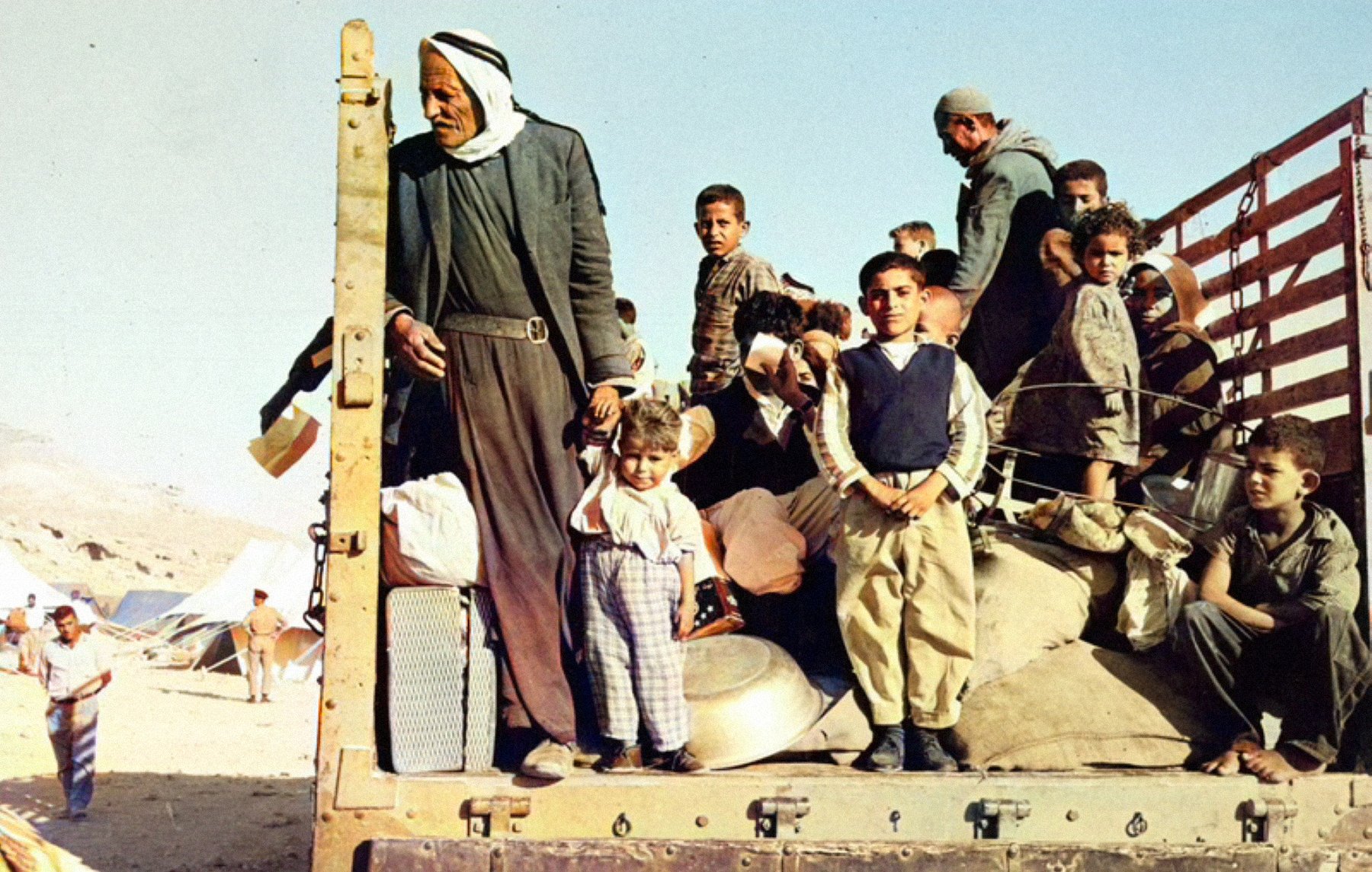Un groupe de personnes, dont des enfants, se tient sur un camion en plein désert.