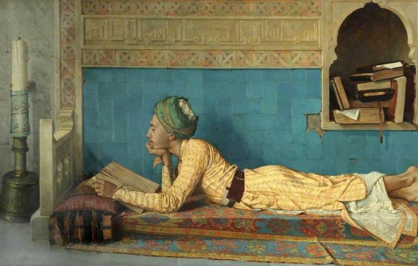 L'image représente un jeune homme allongé sur un tapis, plongé dans la lecture d'un livre. Il porte une tenue traditionnelle aux couleurs vives et un turban. L'arrière-plan est orné de motifs décoratifs et comprend une alcôve où sont disposés quelques livres. À gauche, une bougie sur un support éclaire la scène, créant une atmosphère calme et studieuse. L'ensemble évoque un moment de tranquillité et de contemplation.