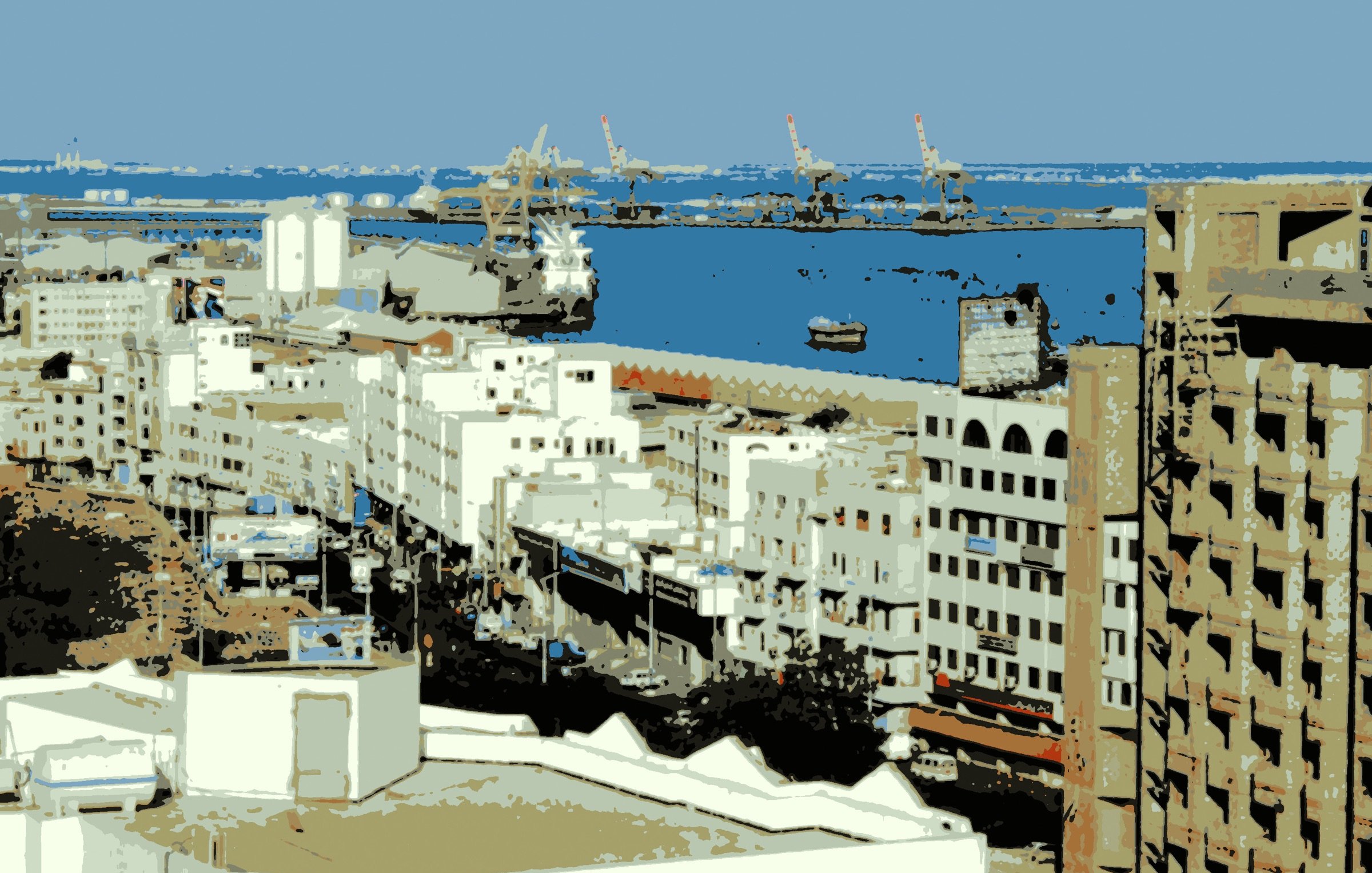 L'image montre un paysage urbain avec des bâtiments blancs et modernes. On aperçoit une vue sur le port, avec des navires et des grues au loin. Le ciel est clair, ce qui laisse transparaître une ambiance paisible. Les structures architecturales semblent principalement de couleur claire, créant un contraste avec la mer bleue. C'est une scène qui évoque l'activité maritime et la vie urbaine.