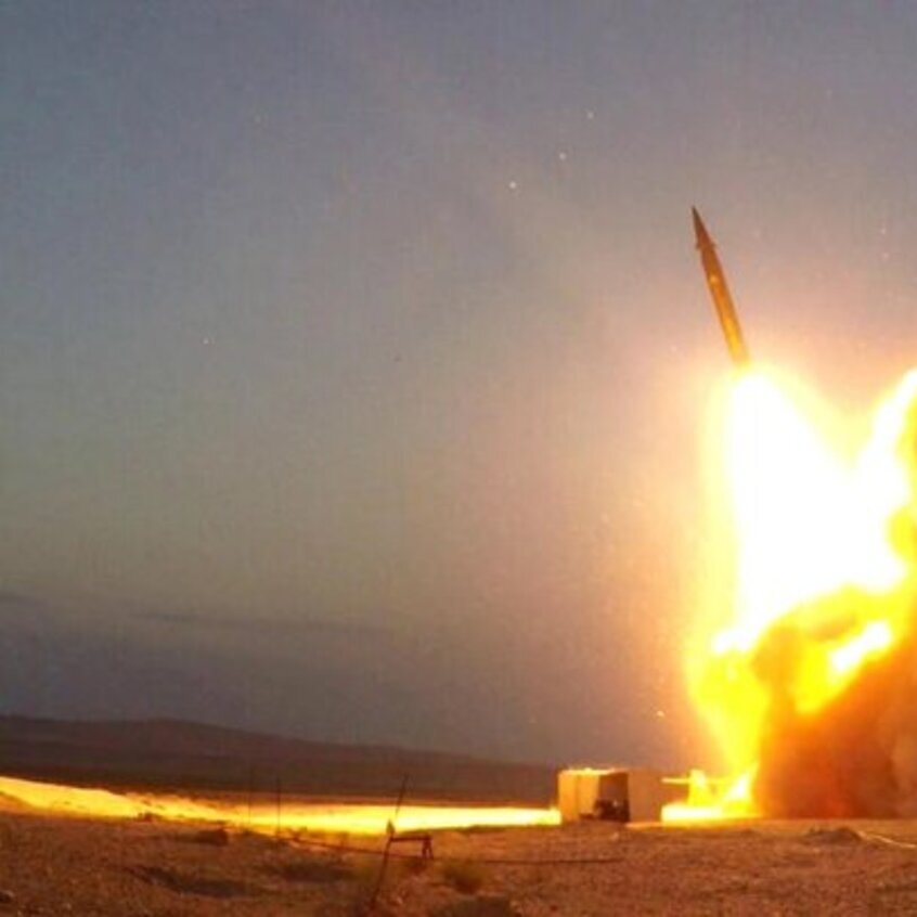 تصویر نشان‌دهنده‌ی پرتاب یک موشک است. در این صحنه، لحظه‌ای از پرتاب موشک به تصویر کشیده شده که شعله‌های آتش و دود فراوانی به سمت آسمان منتشر می‌شود. موشک به طور عمودی از یک سکوی پرتاب خارج شده و محیط اطراف آن نیز کاملاً روشن شده است. نور ناشی از آتش و انفجار به وضوح در تصویر قابل مشاهده است و زمینه نیز به وضوح نشان‌دهنده‌ی زمین خشک و بیابانی است.