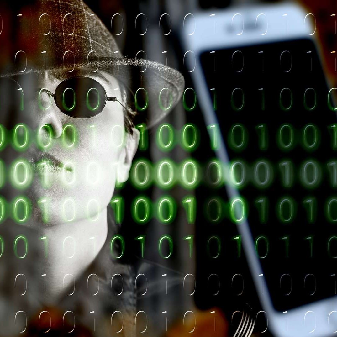 The image features a person wearing a hat and sunglasses, giving a mysterious or secretive vibe. In the background, there is a smartphone and a pattern of green binary code (0s and 1s) overlaying the scene. This combination evokes themes of technology, surveillance, and the digital world. The overall tone suggests a connection to hacking or cybersecurity.