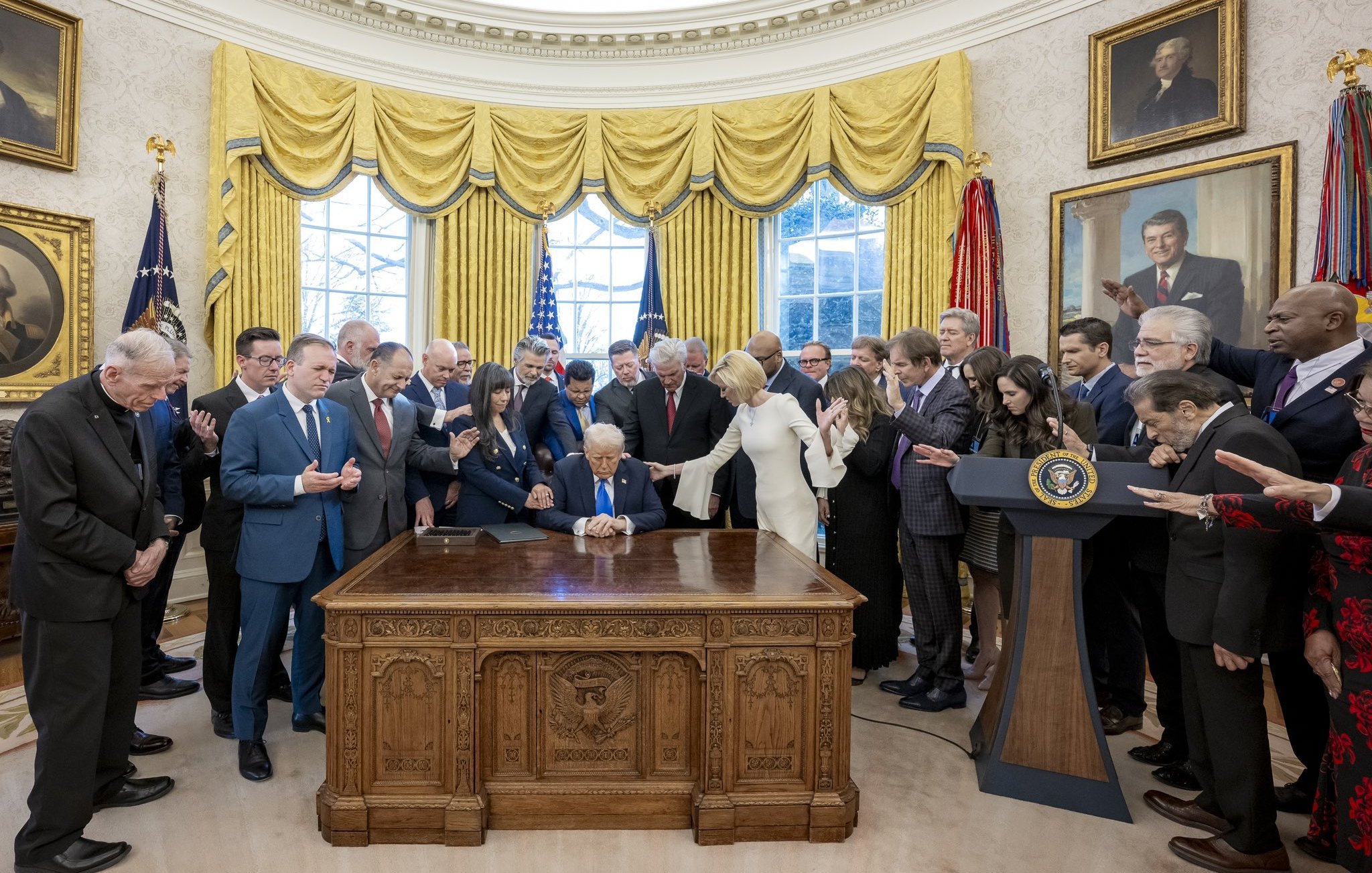 Groupe d'hommes et femmes autour d'un bureau, avec une personne signant un document.