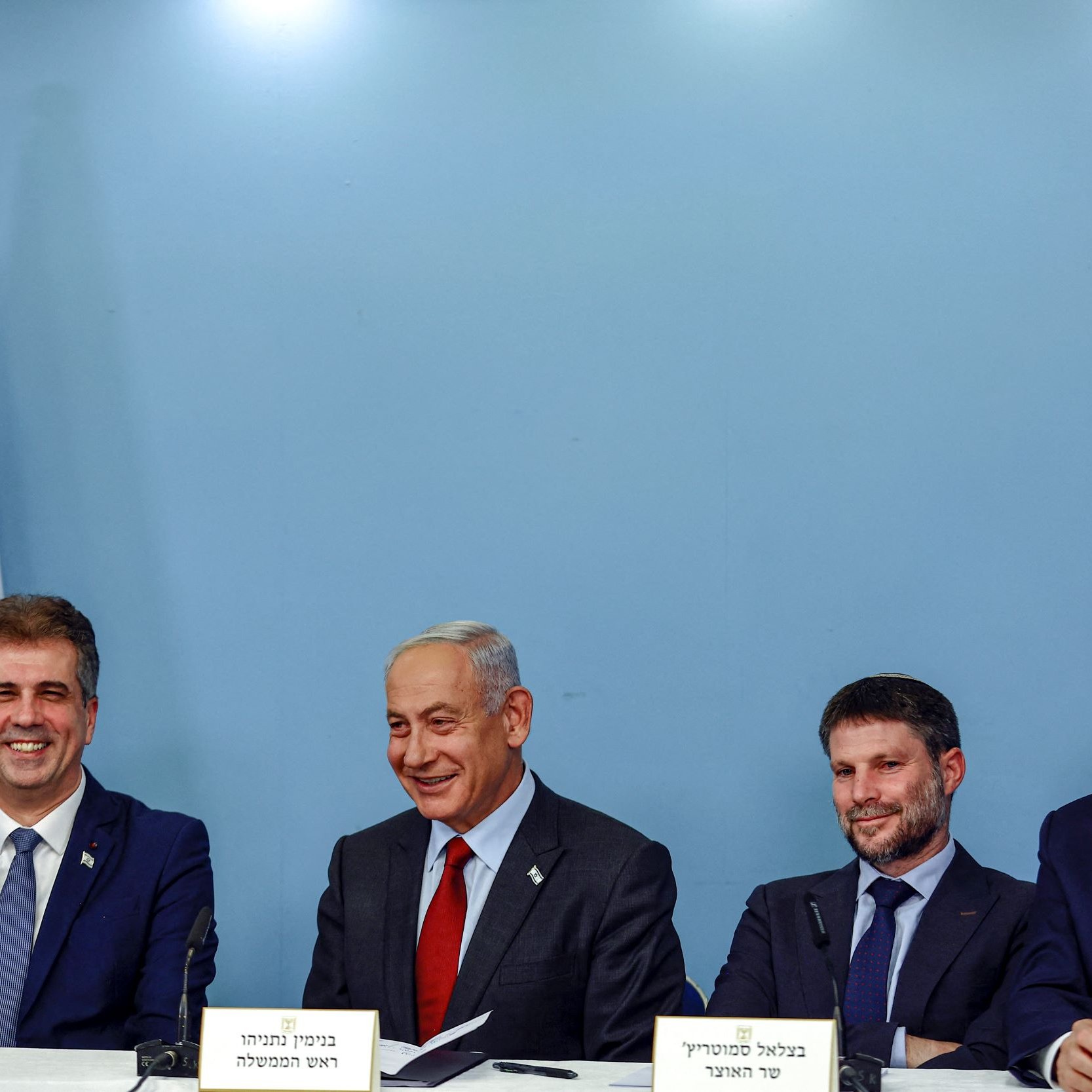 الصورة تظهر مجموعة من الرجال الجالسين حول طاولة في مؤتمر صحفي، مع العلم الإسرائيلي خلفهم. يُظهر تعبير وجوههم الابتسامة والجدية، مما يُشير إلى أنه حدث رسمي أو سياسي. يُمكن أن تكون هذه اللقاءات مرتبطة بقضايا حكومية أو سياسية في إسرائيل.