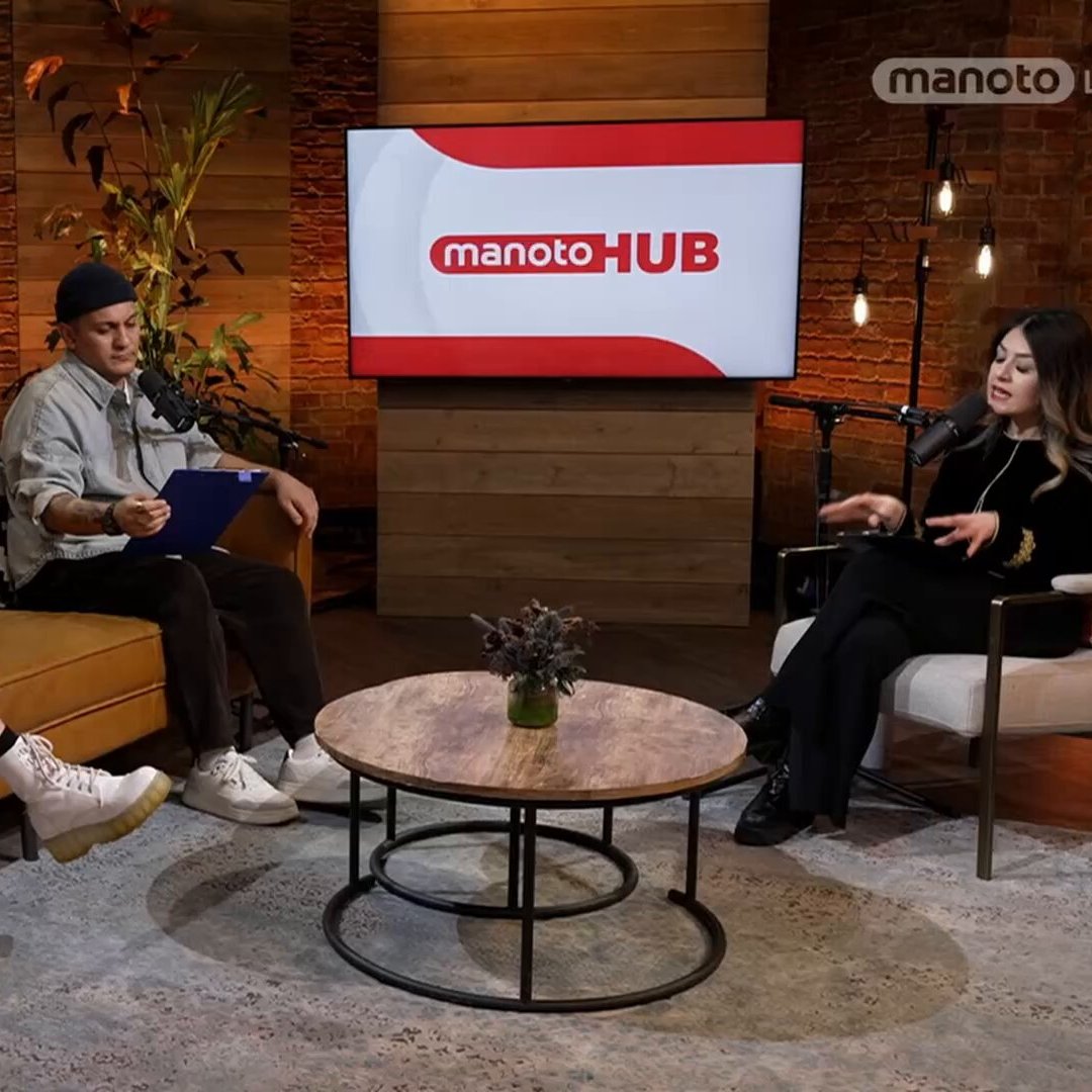 Trois personnes discutent dans un salon moderne, avec un écran au fond.