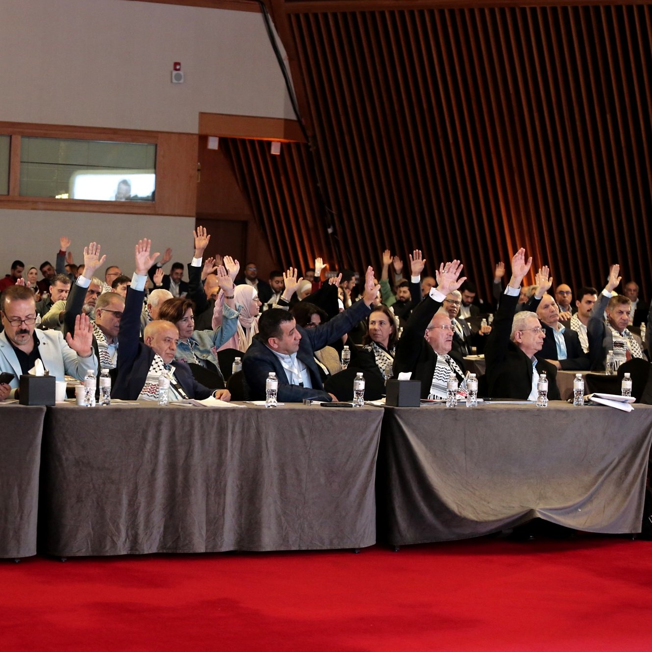 Salle de réunion avec des participants levant la main pour voter.