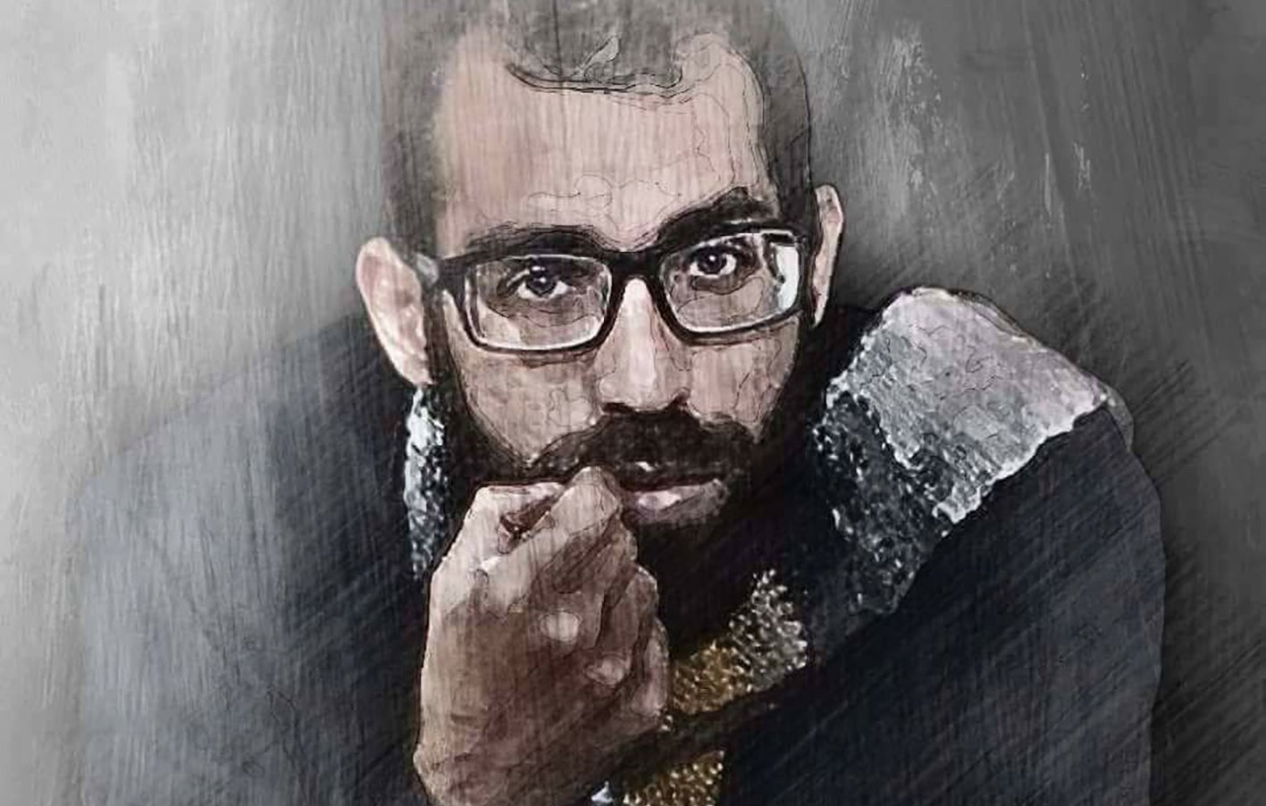 L'image montre un homme avec des lunettes, au regard intense, qui semble réfléchissant. Il a une barbe et porte un vêtement sombre avec des détails clairs. Le fond est flou et évoque une ambiance artistique ou mélancolique. Les traits de son visage sont bien définis, ce qui attire l'attention sur son expression.