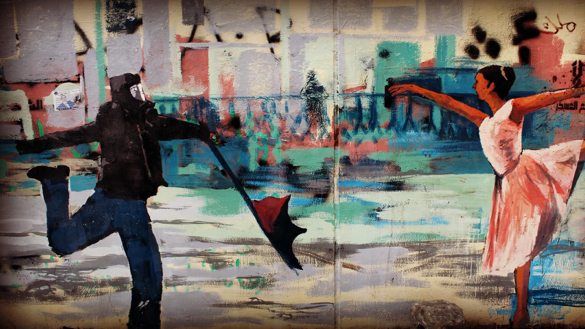 L'image montre une œuvre de street art. À gauche, on voit un homme portant un masque, habillé de noir, qui tient un parapluie ouvert. À droite, une ballerine en robe blanche exécute une danse gracieuse. Le fond de l'œuvre est rempli de couleurs vives et de formes abstraites, créant une atmosphère dynamique. Cette juxtaposition entre les deux personnages évoque un contraste entre l'agitation du monde urbain et la beauté de la danse.
