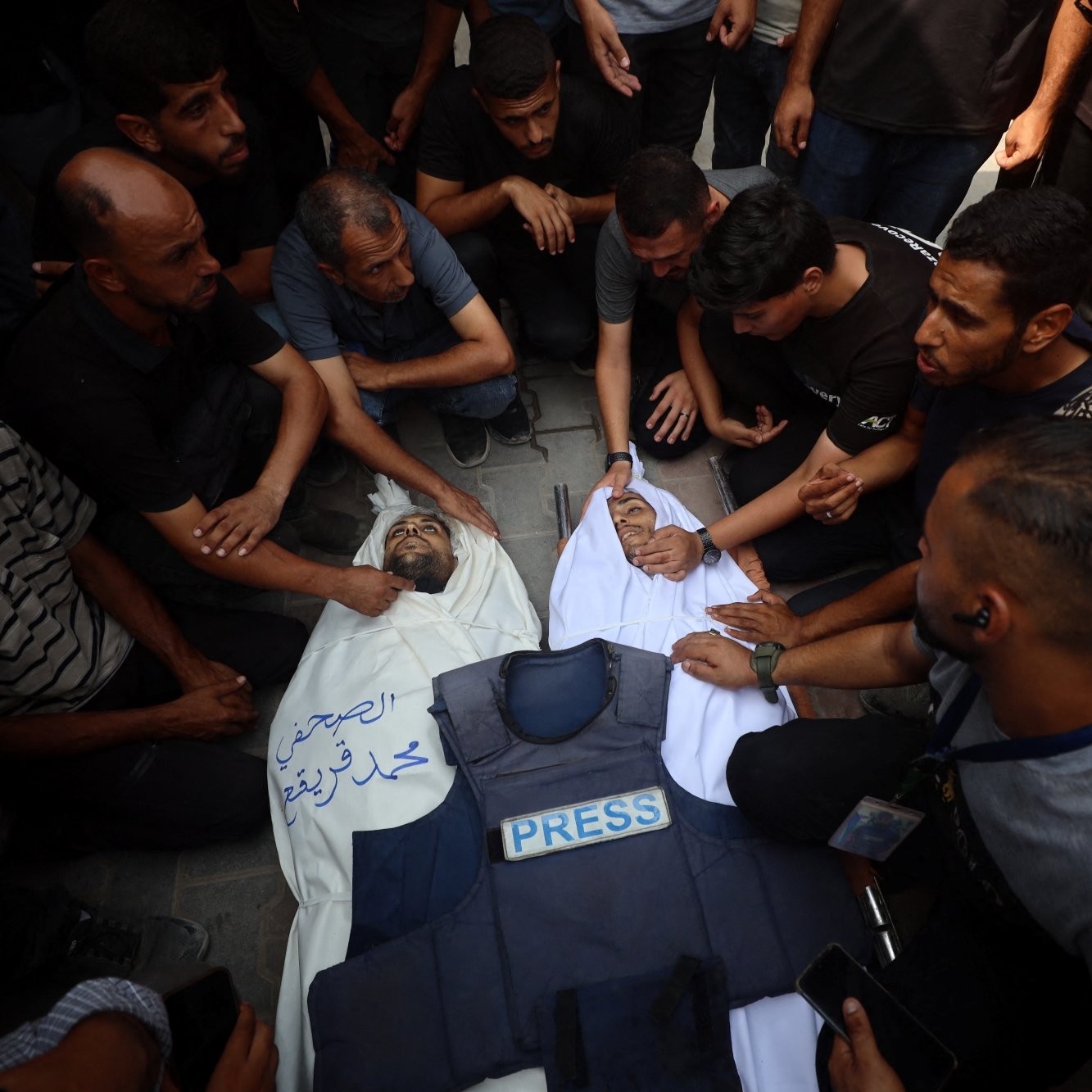 Un gruppo di persone attorno a un corpo coperto, in segno di lutto e protesta.