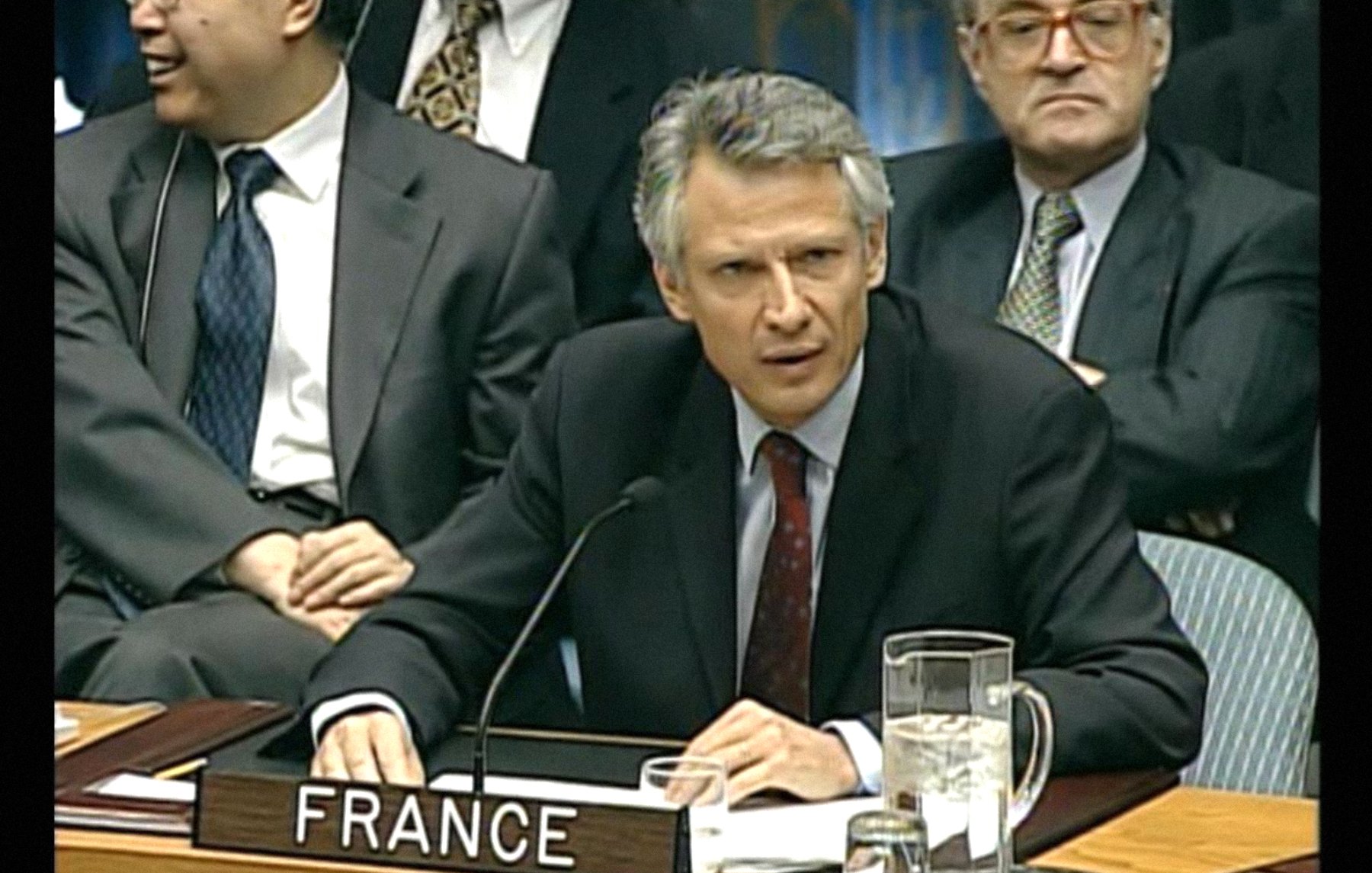 Homme en costume, sérieux, représentant la France lors d'une réunion officielle.