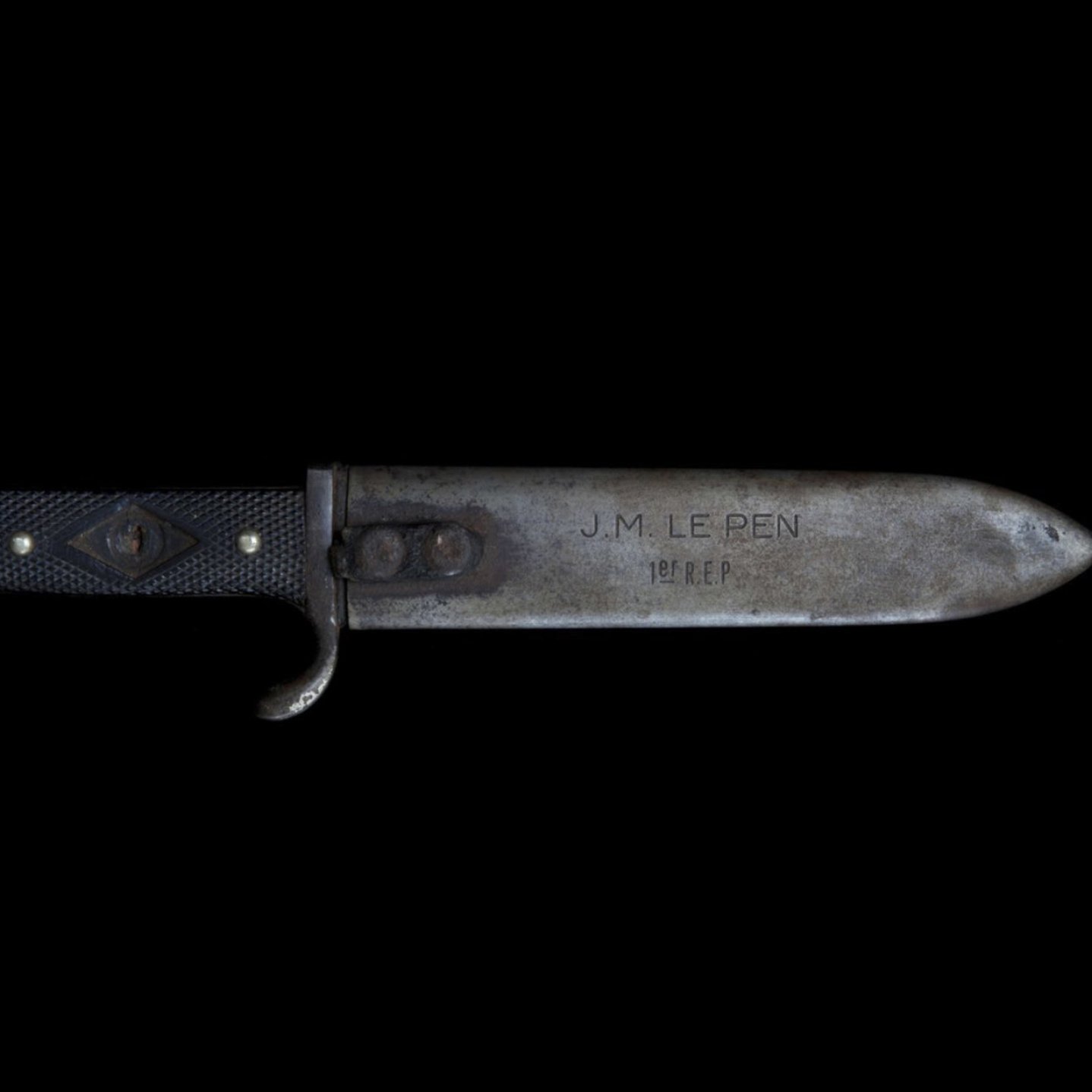 Un couteau avec une lame métallique et un manche noir, gravé d'inscriptions.