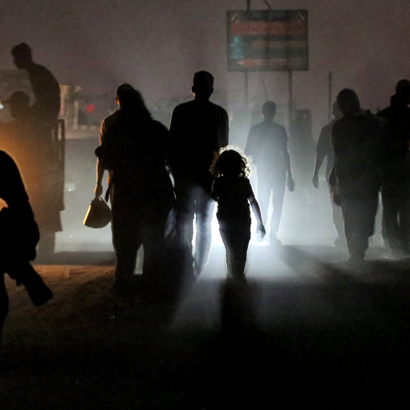 Una fila di persone in silhouette, una bambina con una luce al centro, in un'atmosfera misteriosa.