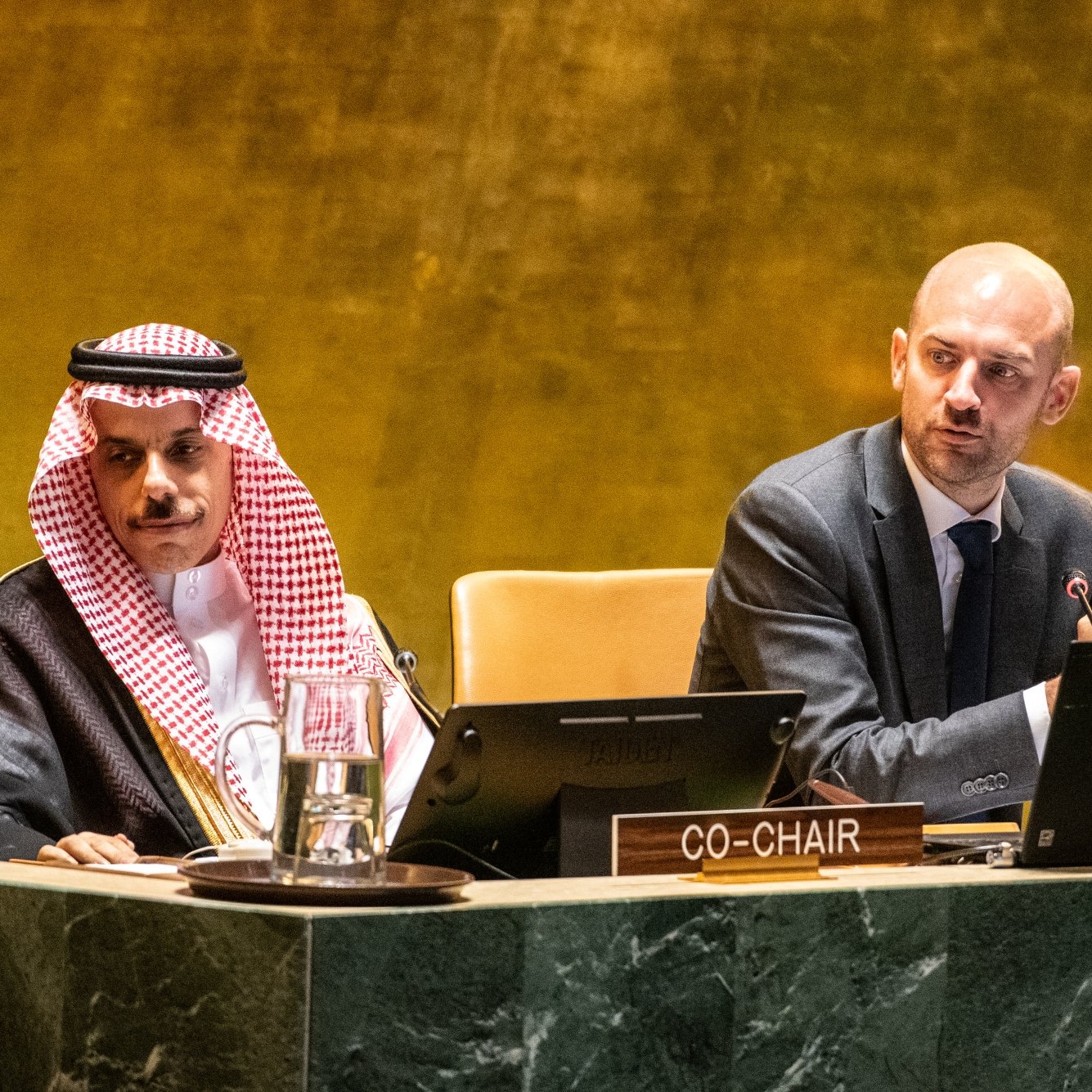 Deux hommes en costume assis à une table dans une salle de conférence.