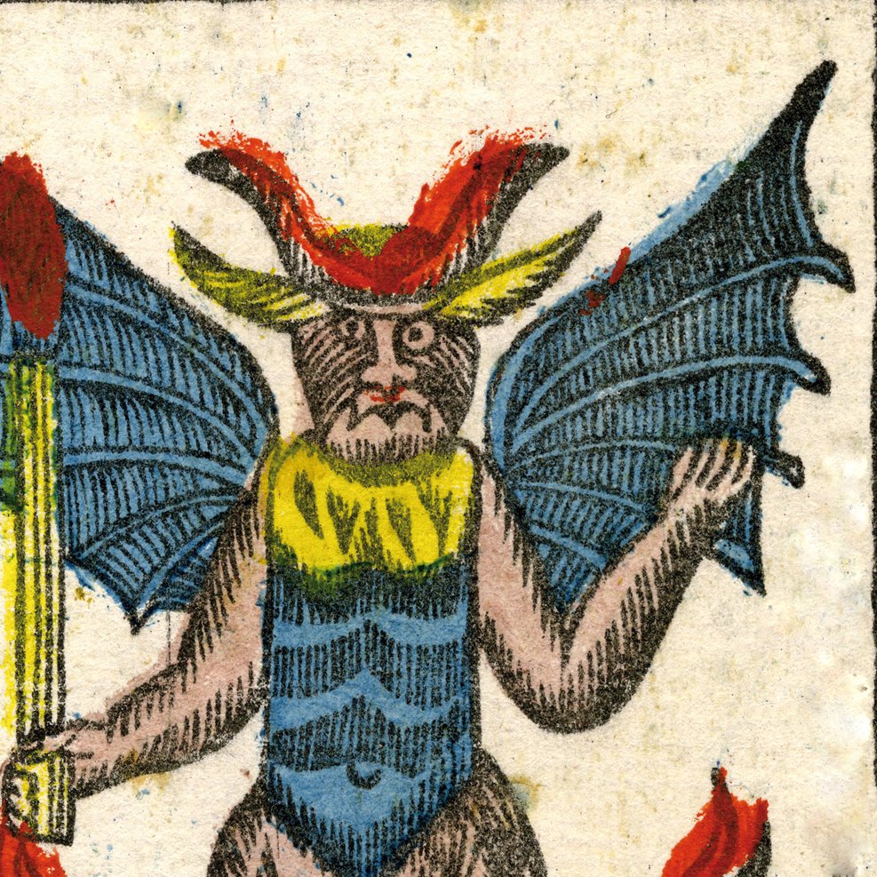 الصورة تظهر كائنًا خياليًا له مظهر يشبه الشيطان أو الوحش. يمتلك أجنحة كبيرة تشبه أجنحة الخفافيش، ومخالب، ومظهرًا جسديًا يجمع بين الصفات البشرية والحيوانية. يرتدي الكائن ملابس ملونة، حيث يظهر بجسم عارٍ مع تفاصيل على الصدر، ورأسه مزين بقرون. في يده يحمل عصا، مما يضفي على الصورة جواً من الغموض والرعب. الألوان المستخدمة في الصورة زاهية وتساعد في تعزيز مظهر الكائن الخيالي.