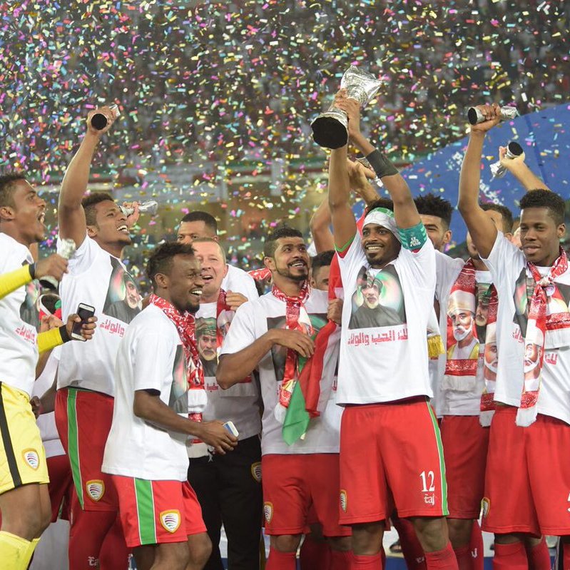 L'image montre une équipe de football célébrant une victoire. Les joueurs, vêtus de maillots assortis avec des t-shirts, levant un trophée en l'air, entourés de confettis multicolores. Ils semblent joyeux et enthousiastes, exprimant leur bonheur après avoir remporté un titre, probablement lors d'un tournoi ou d'une compétition. Les supporters en arrière-plan ajoutent à l'atmosphère festive.