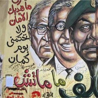 L'image représente une fresque murale avec des portraits de figures politiques, accompagnée de textes en arabe et d'autres éléments graphiques. Les visages semblent se faire face de manière marquante, probablement pour symboliser des conflits ou des idées politiques. Les inscriptions en arabe pourraient évoquer des slogans ou des messages liés à la politique ou à la société. L'utilisation de couleurs vives et de styles artistiques renforce l'impact visuel de cette œuvre.