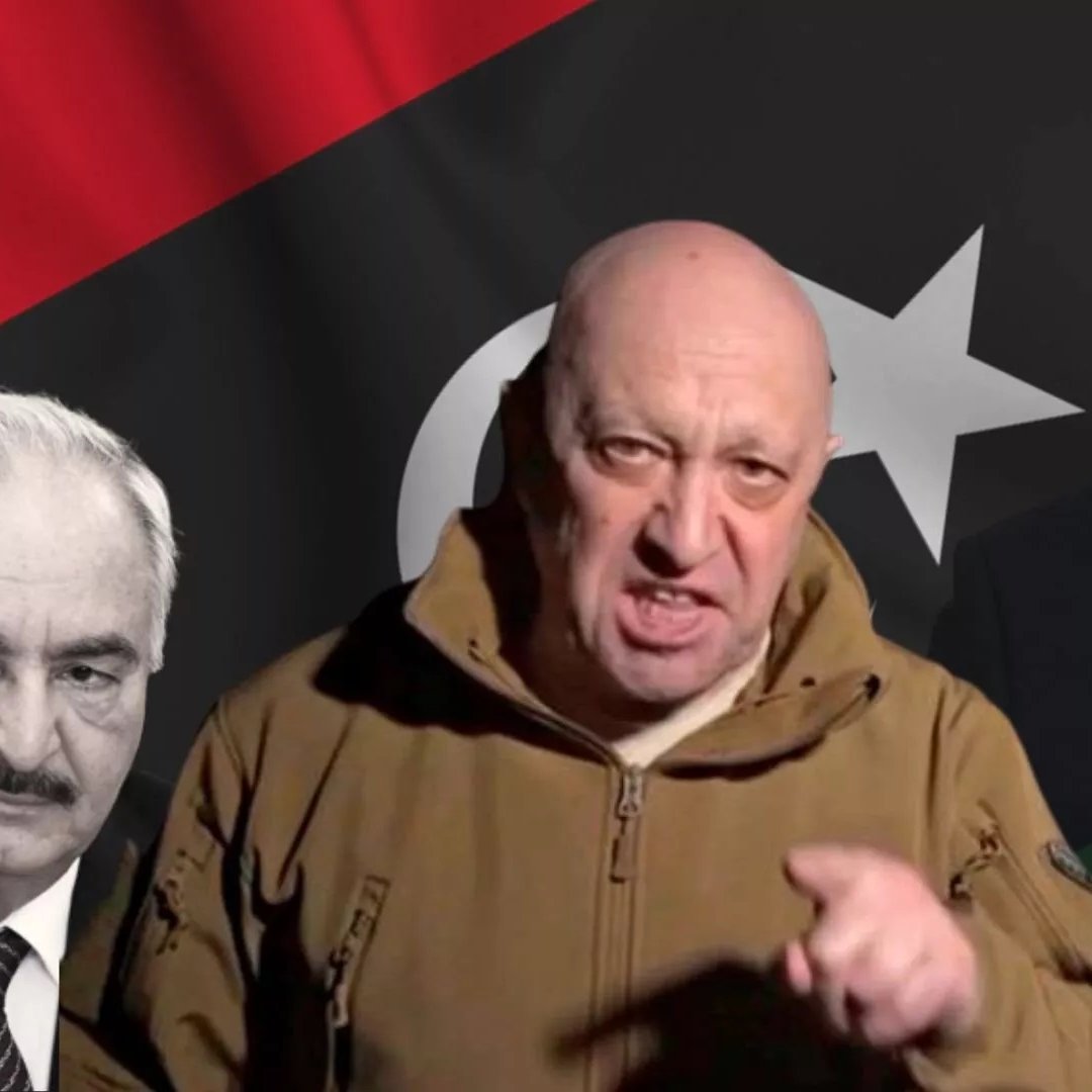 L'image présente un homme au premier plan, portant une veste kaki et exprimant visiblement une émotion forte. En arrière-plan, il y a des drapeaux, notamment un drapeau libyen avec des couleurs rouge, noir, et vert, ainsi qu'une étoile et un croissant. De chaque côté de l'homme, on peut voir deux silhouettes ou visages flous, qui représentent probablement des figures politiques. L'atmosphère de l'image semble tendue, avec des éléments visuels qui suggèrent un contexte politique ou militaire.