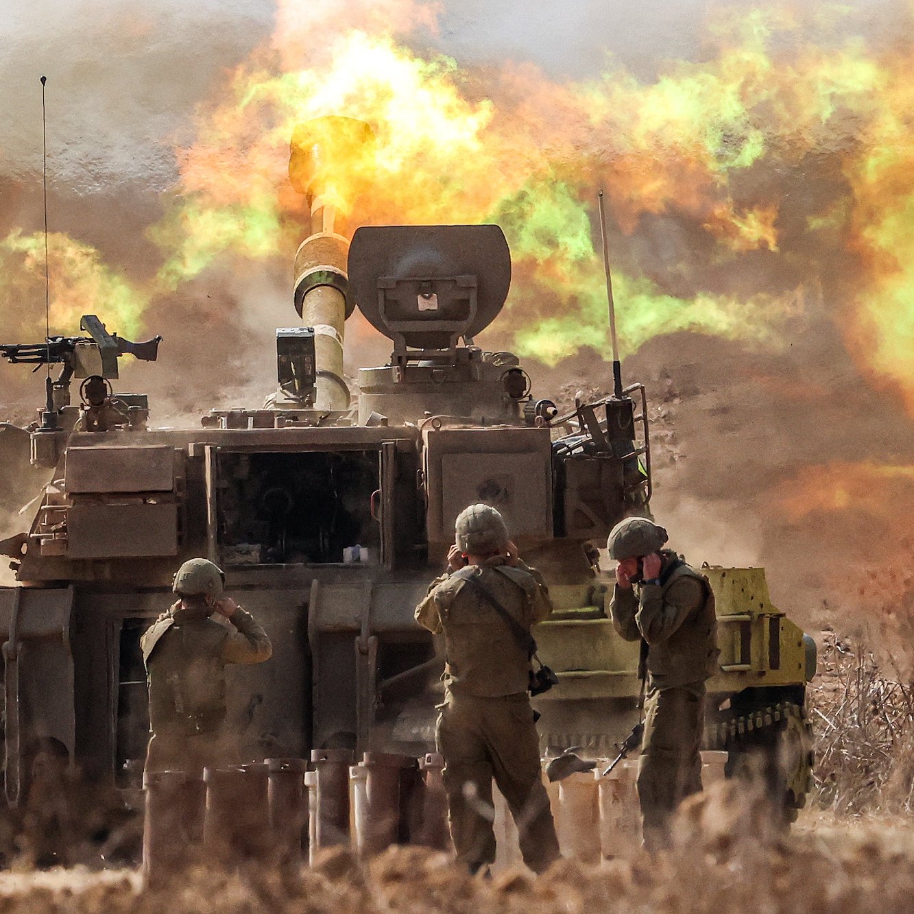 در این تصویر، یک تانک نظامی را مشاهده می‌کنیم که در حال شلیک است. دود و شعله‌های آتش به شدت از دهانهٔ توپ تانک بیرون می‌آید و فضای اطراف را پر از دود کرده است. چند نفر نظامی در مقابل تانک ایستاده‌اند و به وضوح مشغول انجام وظایف خود هستند. محیط پیرامون نیز به نظر می‌رسد که تحت تأثیر فعالیت‌های نظامی قرار دارد، با نمایی غبارآلود و درهم‌ریخته.