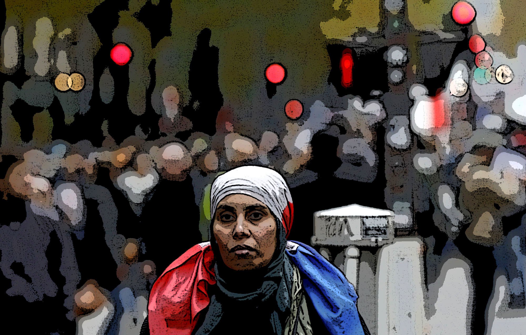 تصویر یک زن را نشان می‌دهد که به سمت دوربین نگاه می‌کند و روی دوش او یک پرچم، احتمالاً پرچم فرانسه، قرار دارد. او به نظر می‌رسد در یک خیابان شلوغ ایستاده است و جمعیتی در پس‌زمینه دیده می‌شود. نقاط نورانی و رنگی در پس‌زمینه به تصویر حس شهری و پویایی می‌دهند. خانم در تصویر حجاب بر سر دارد و احساس جدیت و تمرکز را منتقل می‌کند.