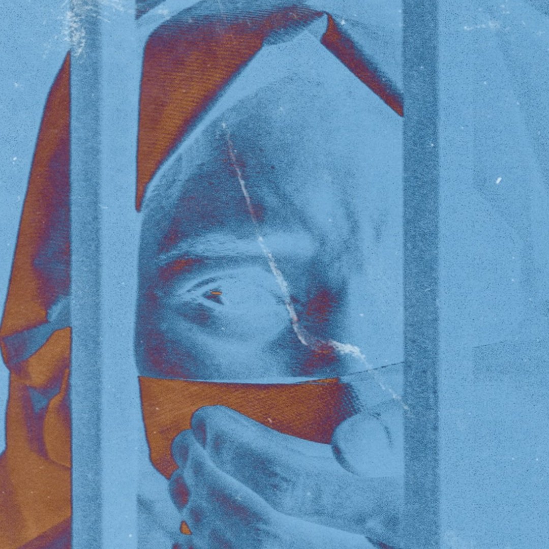 L'immagine presenta un effetto stilizzato e astratto, con tonalità blu predominanti. Si possono notare delle barre verticali che creano un senso di prigionia o separazione. Un volto, parzialmente visibile, sembra esprimere emozione, con dettagli sfocati che potrebbero suggerire vulnerabilità o paura. La mano in primo piano stringe un oggetto, contribuendo a trasmettere una sensazione di tensione. L'intero contesto visivo evoca riflessioni su isolamento e introspezione.