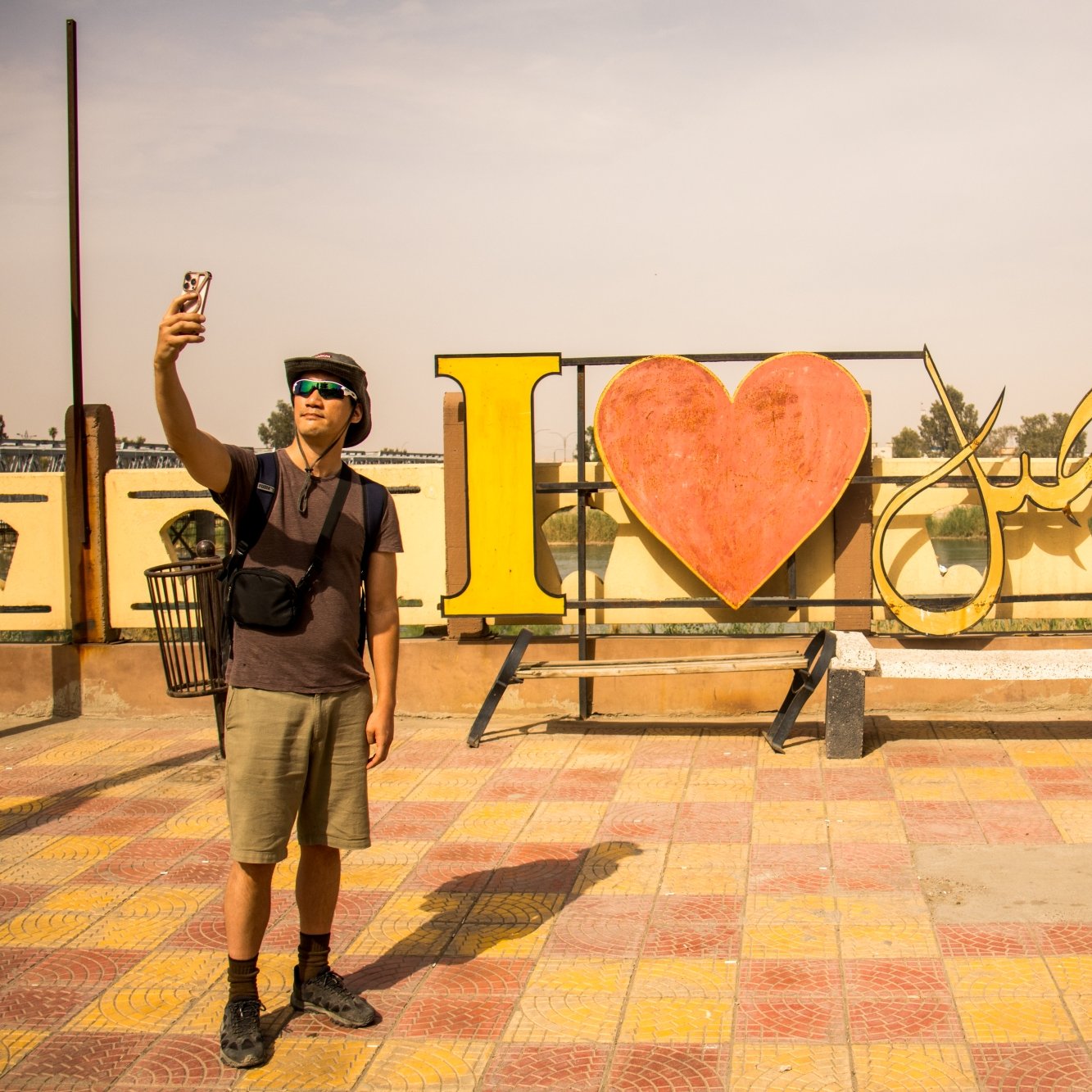 Un homme prend un selfie devant une grande inscription colorée "I ❤️ [nom]".