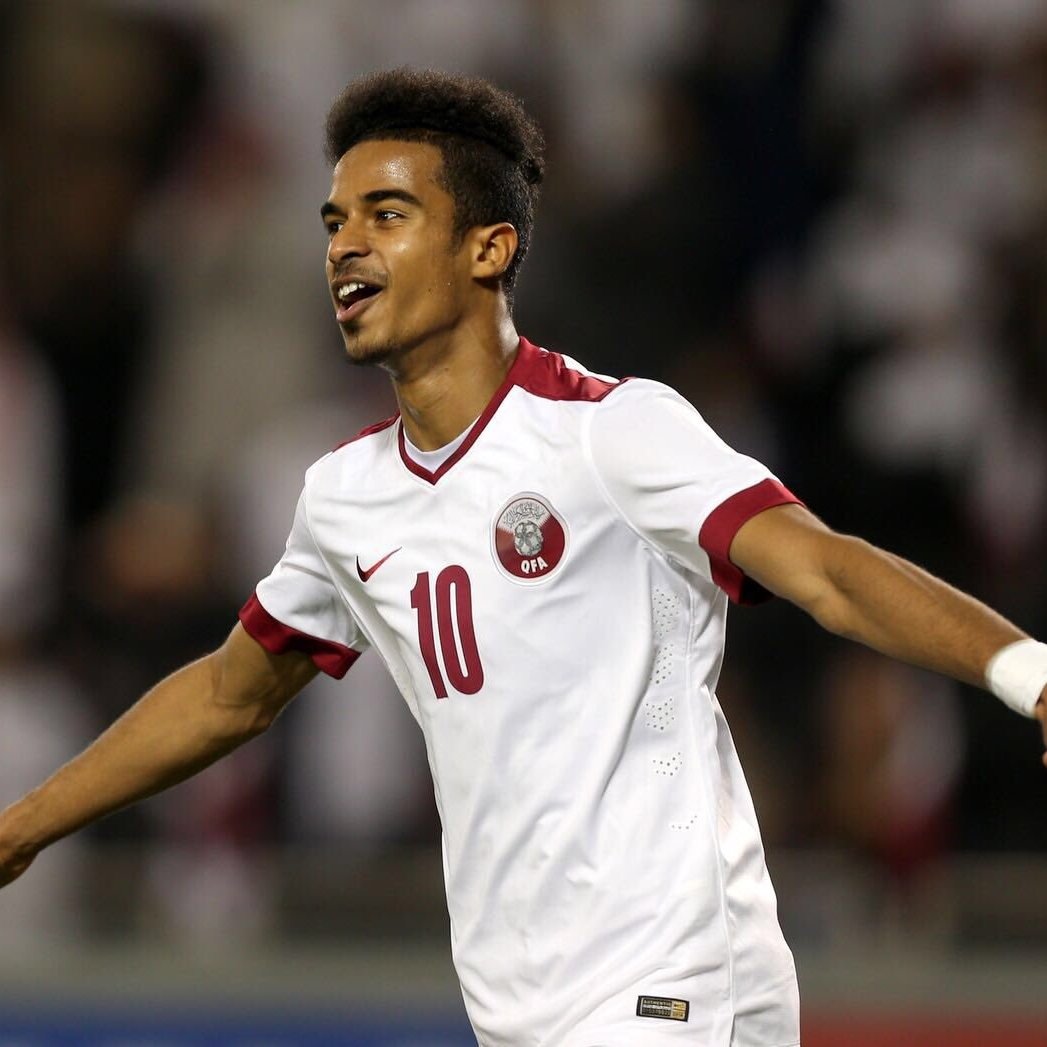 L'image montre un jeune joueur de football qui célèbre un but. Il porte un maillot blanc avec des touches de rouge, et le numéro 10 est visible sur son dos. Son expression est joyeuse et dynamique, manifestant sa satisfaction après une action réussie. En arrière-plan, on aperçoit des supporters, probablement vêtus de blanc, ce qui suggère un événement sportif important. La scène dégage une énergie positive et une intensité propre au football.