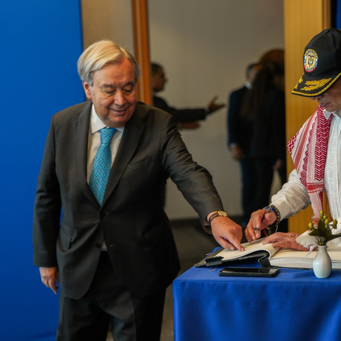 دو مرد در یک اتاق هستند. یکی در حال نوشتن در کتابی روی میزی کوچک است و دیگری نظاره می‌کند.