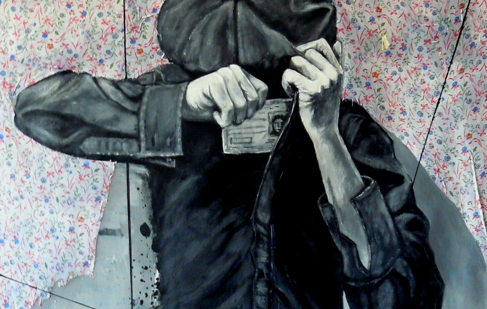 L'image représente une œuvre d'art qui illustre une personne de dos, portant une casquette. Cette figure est en train de prendre une photo avec un appareil photographique. Le style de l'œuvre est en noir et blanc, ce qui lui donne une atmosphère intense et mystérieuse. Le fond est décoré d'un motif floral coloré, contrastant avec la monochromie du personnage. L'ensemble crée un effet visuel captivant, où le personnage semble émerger d'un espace clos, symbolisé par des lignes géométriques.