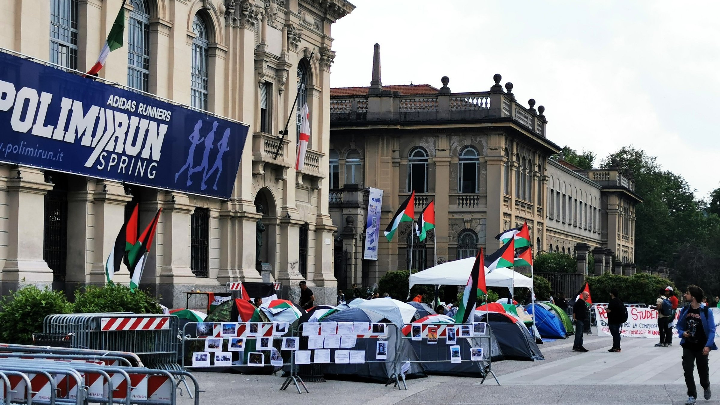 Un campo con tende, bandiere palestinesi e cartelli di protesta.