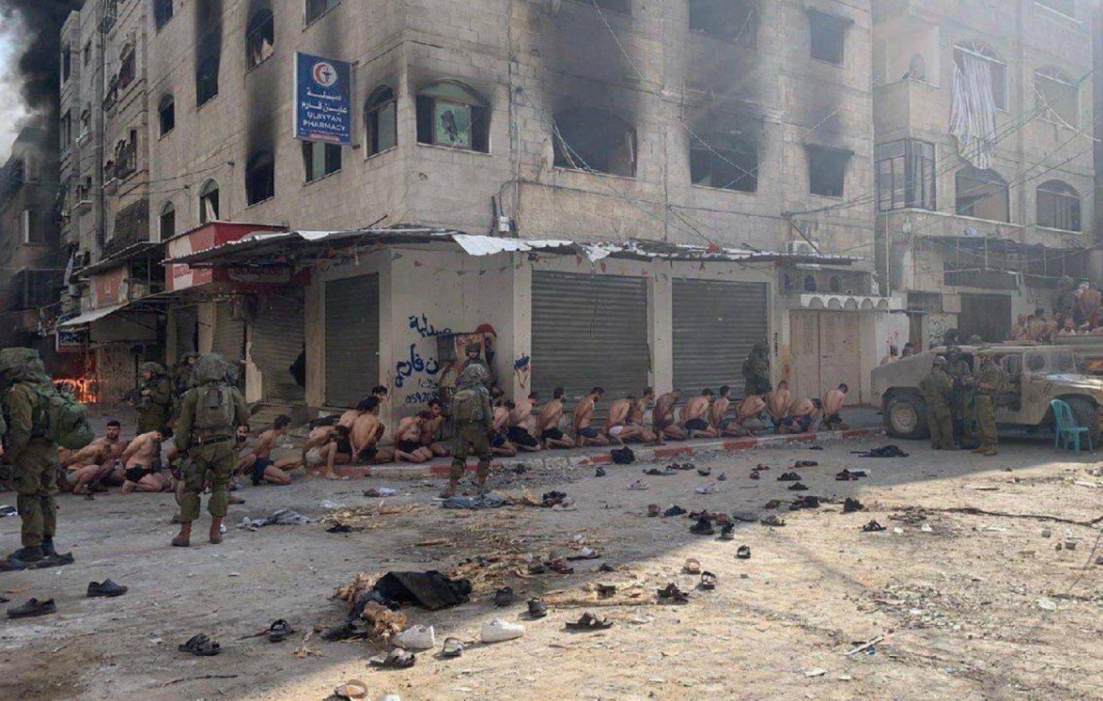 A scene of distress showing people detained in an urban setting with military presence.