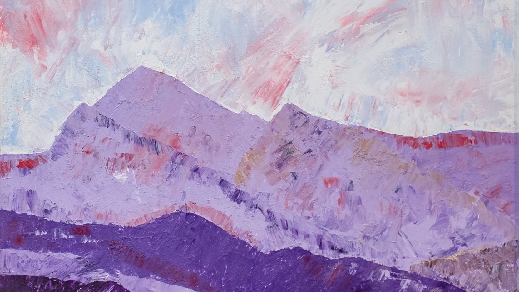 Paysage montagneux aux teintes violettes et rougeâtres sous un ciel nuageux.