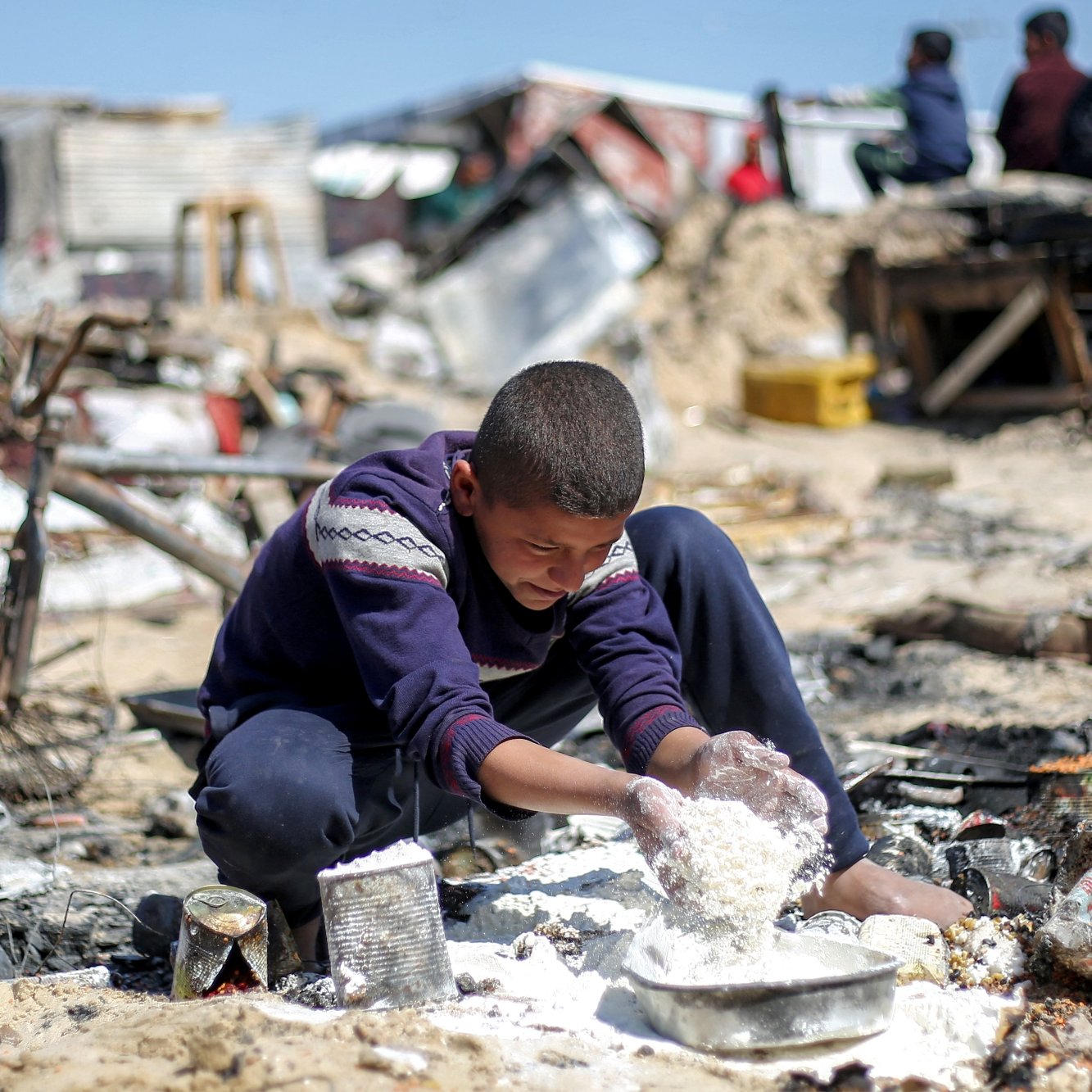 Un garçon joue dans un environnement désordonné, entouré de débris et de ruines.