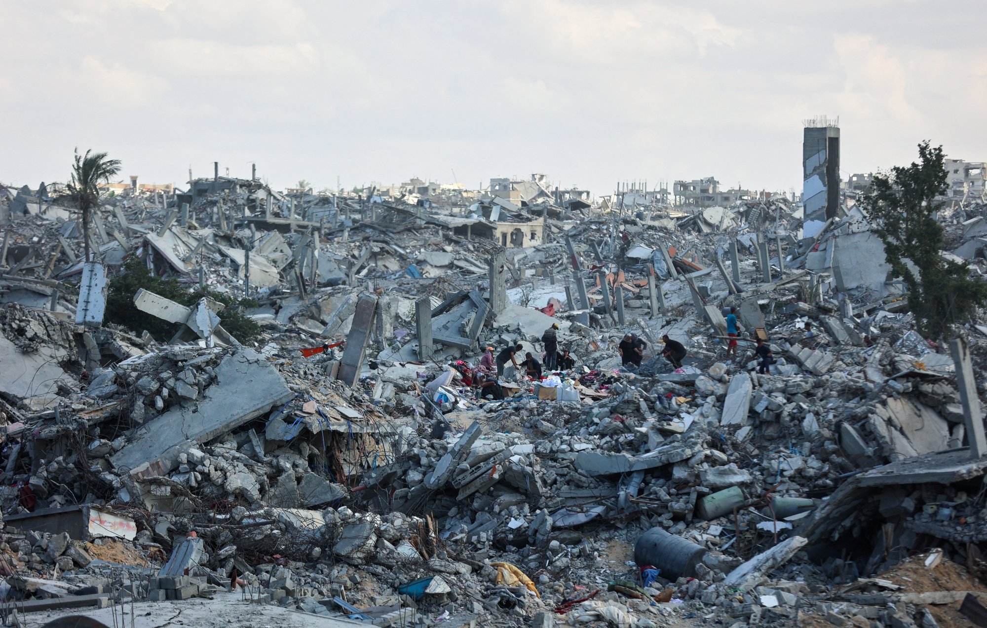 Destruction massive avec décombres et silhouettes humaines cherchant des survivants.