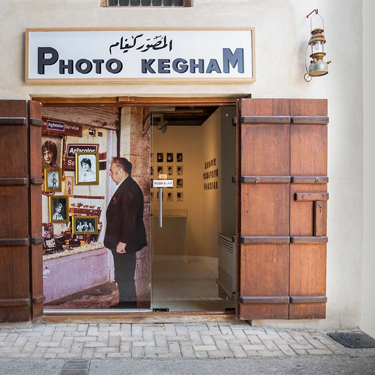 A small photo shop entrance with wooden doors, showcasing images and an exhibit inside.