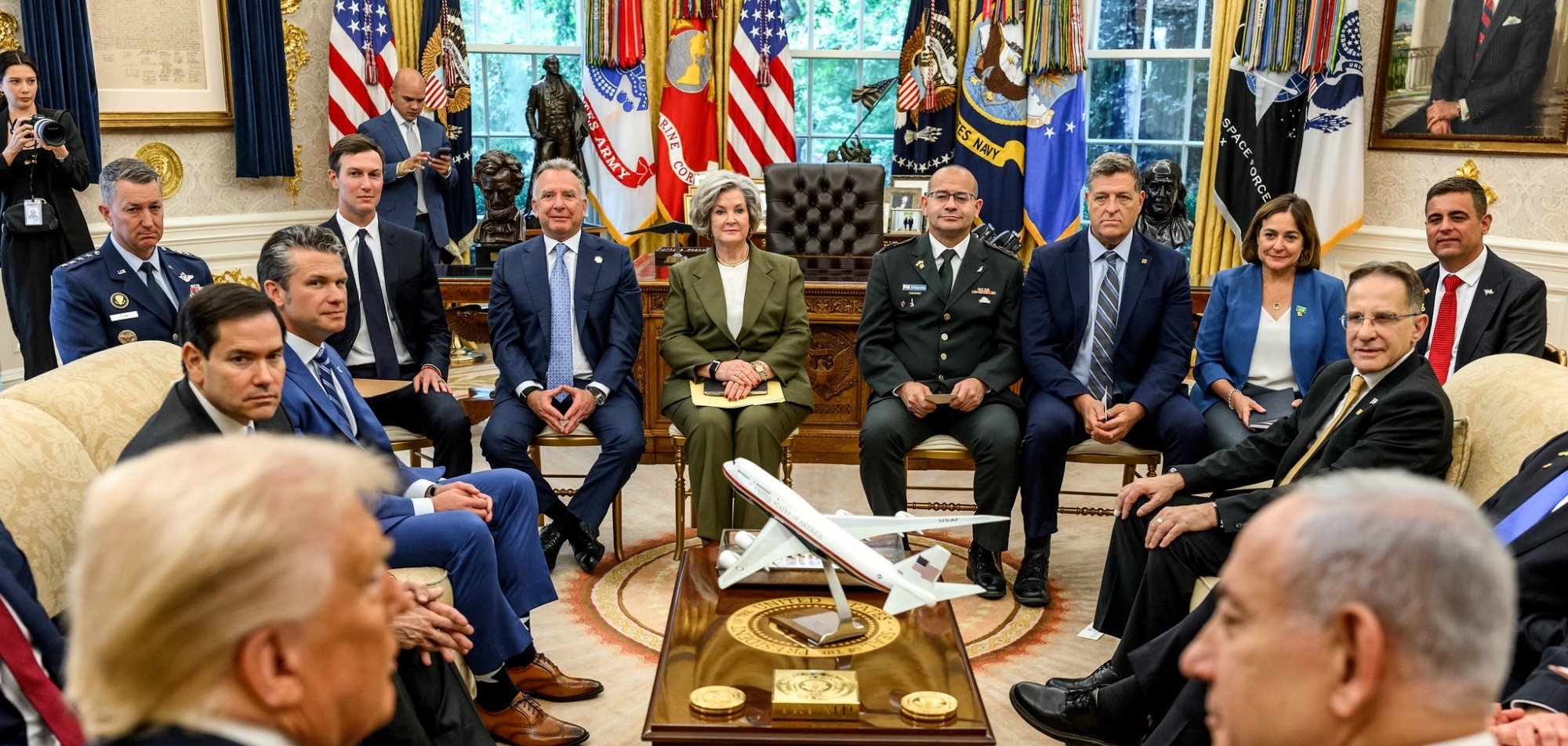 یک جلسه رسمی در اتاق بیضی کاخ سفید، با چندین مرد و زن در حال نشستن دور یک میز.