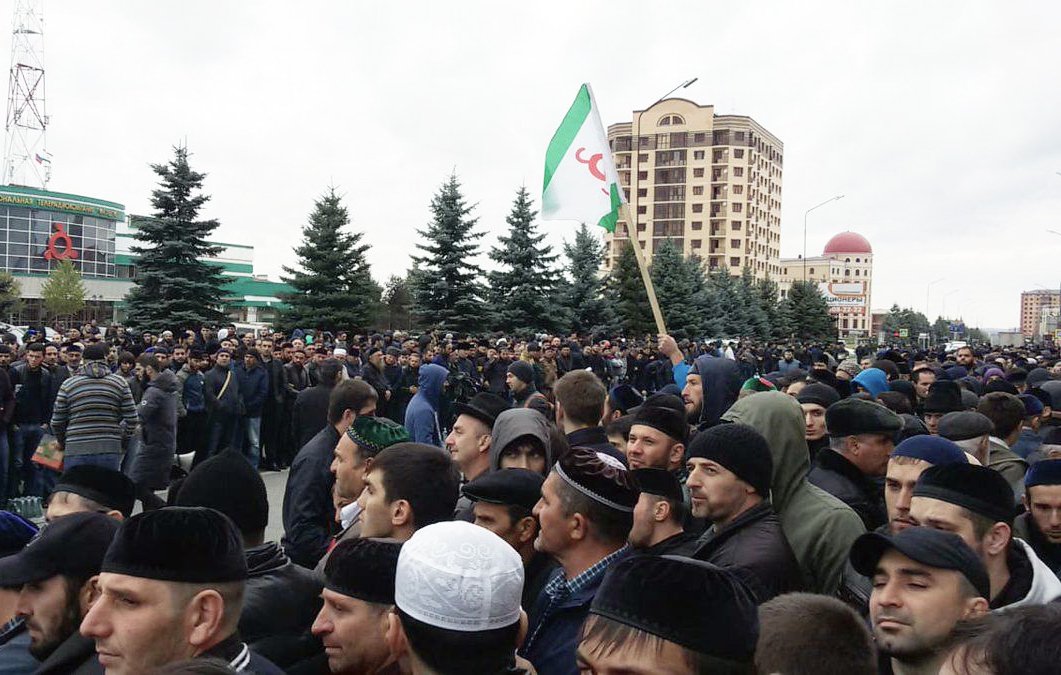 الصورة تظهر تجمعًا حاشدًا من الناس في منطقة حضرية. يبدو أن المحتشدين يرتدون ملابس متنوعة، وهناك بعضهم يحملون لافتات أو أعلام. في الخلفية، توجد مبانٍ شاهقة وأشجار، مما يشير إلى أن هذا التجمع يمكن أن يكون حدثًا اجتماعيًا أو سياسيًا. تبدو السماء ملبدة بالغيوم، مما يعكس أجواء غير مشمسة.