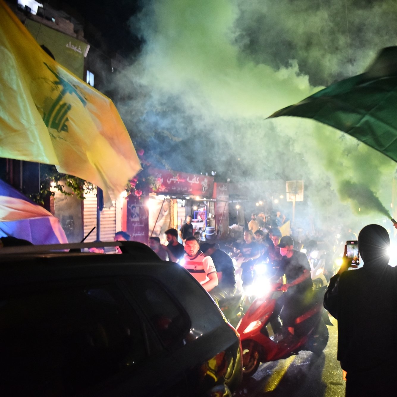 Des manifestants brandissent des drapeaux sous une fumée colorée dans une ambiance festive.