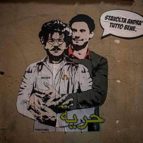 L'immagine mostra un murale che ritrae due figure. Una di esse ha un aspetto distintivo, con occhiali e baffi, mentre l'altra indossa un completo elegante. Sullo sfondo, si può notare un muro di colore neutro, e sopra le figure è presente un testo in italiano che dice "Stai tranquillo, andrà tutto bene". Inoltre, nella parte inferiore della figura è scritta la parola "حرية" (che significa "libertà" in arabo). L'opera sembra trasmettere un messaggio di speranza e solidarietà.