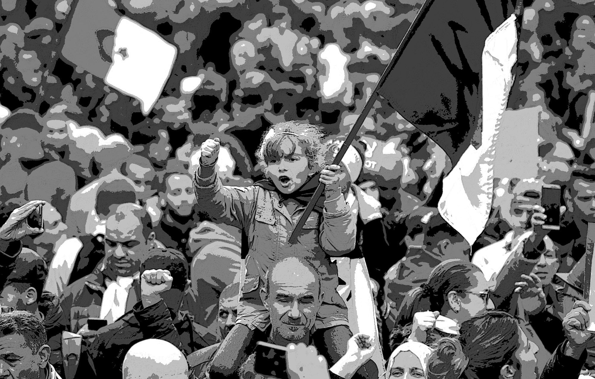 L'image montre une foule rassemblée lors d'une manifestation. Au premier plan, une petite fille se tient sur les épaules d'un adulte, brandissant un drapeau. Elle semble enthousiaste et déterminée, levant le poing. La foule autour d'elle est dense, avec des visages variés et des drapeaux visibles en arrière-plan. L'atmosphère est dynamique et engagée, évoquant un sentiment collectif et de solidarité.
