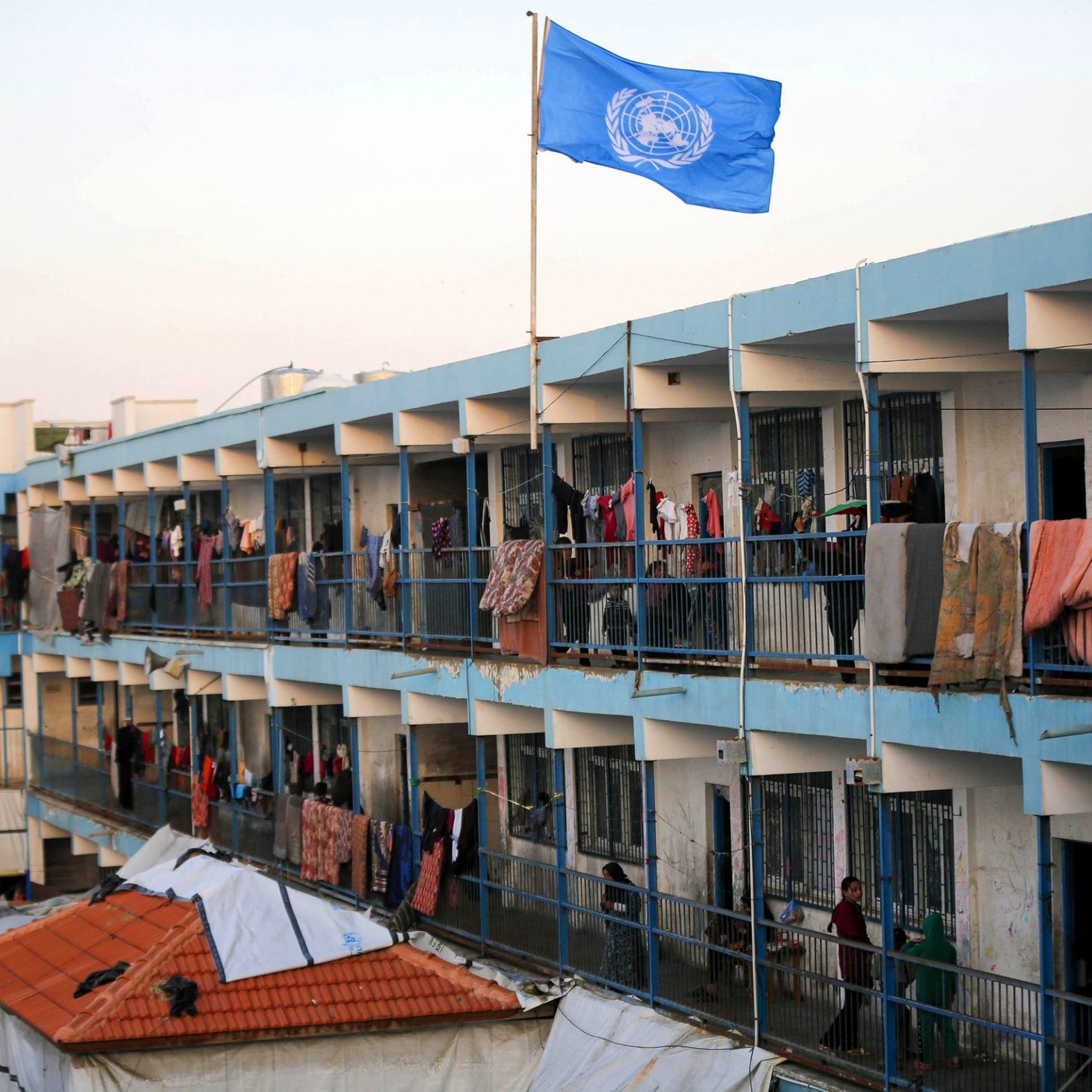 Un edificio con balconi allineati, bandiera ONU e vestiti appesi ad asciugare.