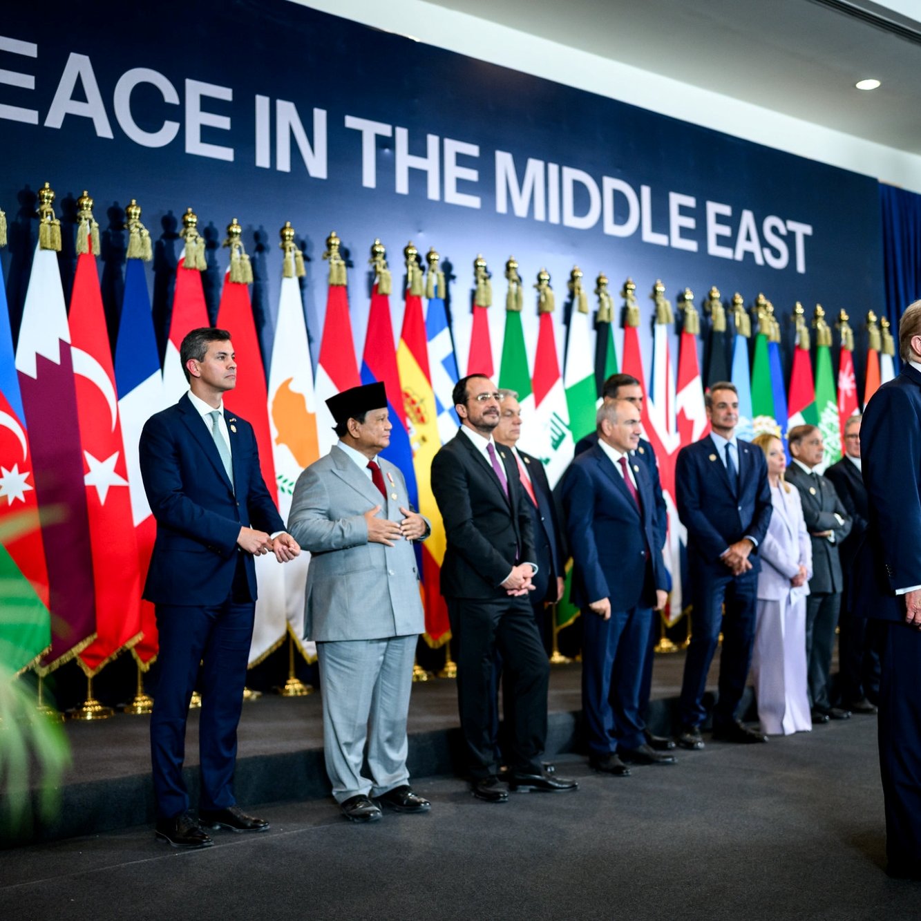 Gruppo di leader con bandiere nazionali sullo sfondo, momento per la pace in Medio Oriente.